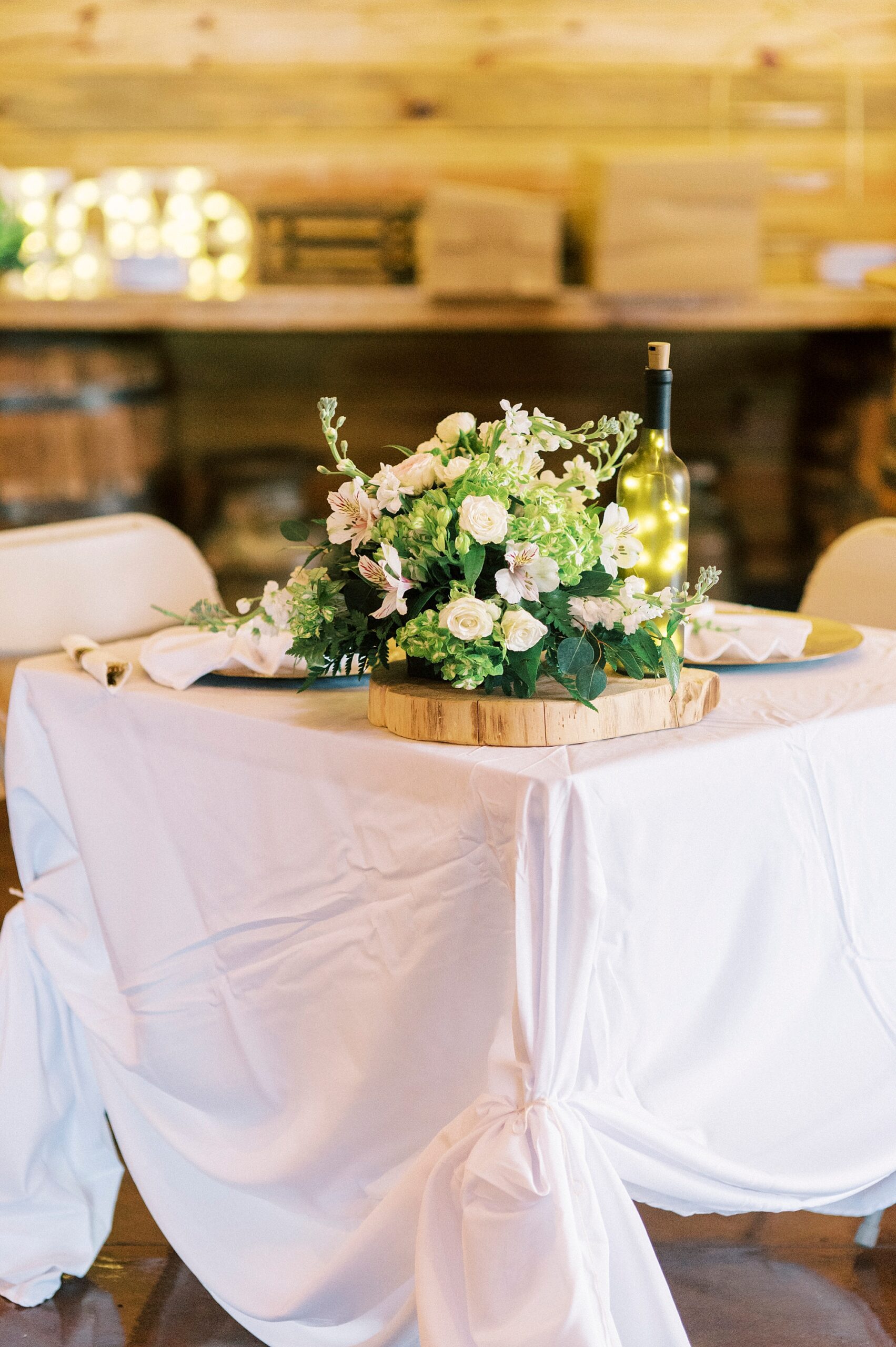 sweetheart table with green and white floral display on wooden charger 