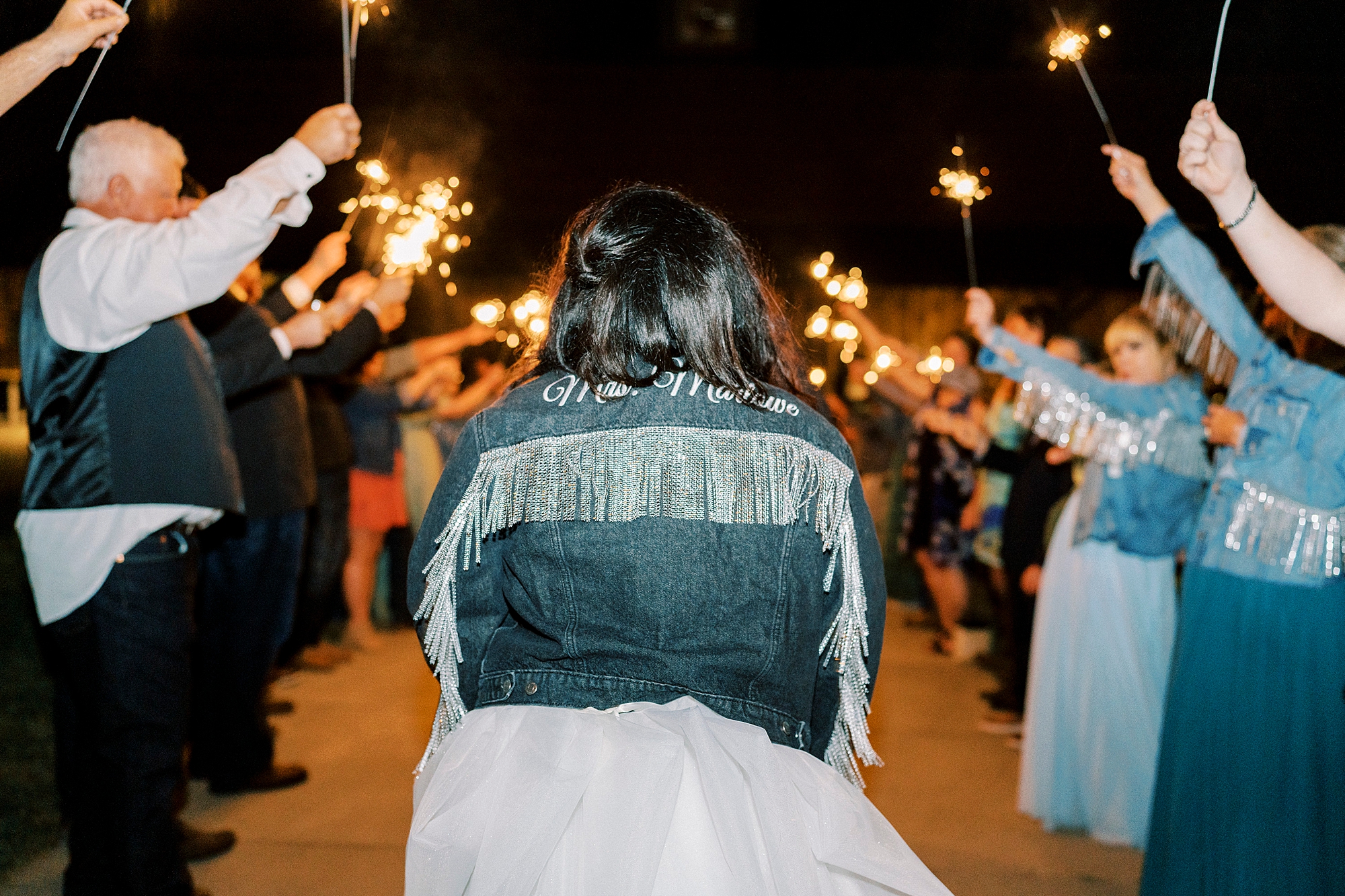 bride shows off custom jean jacket during sparkler exit