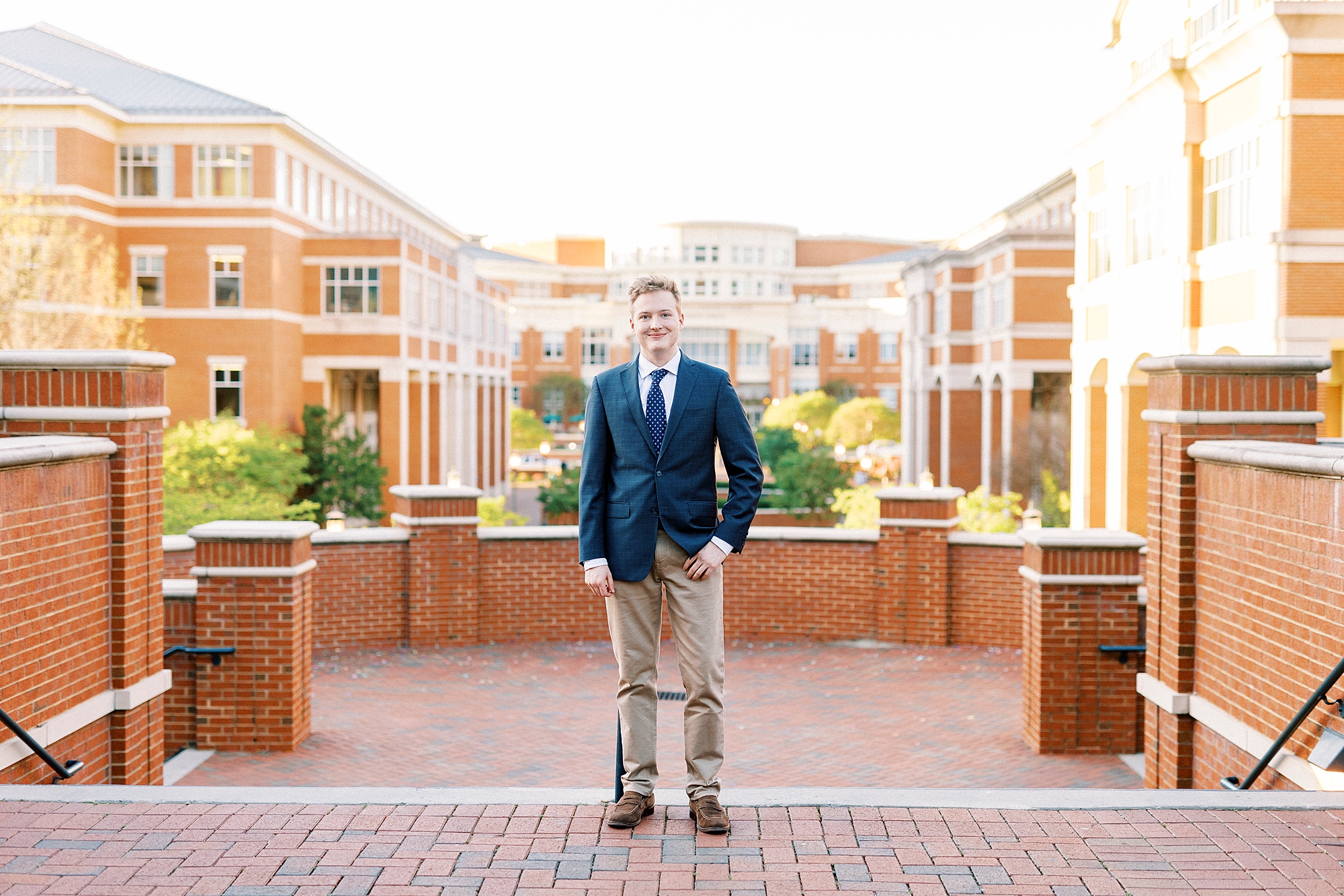 graduating senior in navy blazer and khakis stands on quad at UNC Charlotte