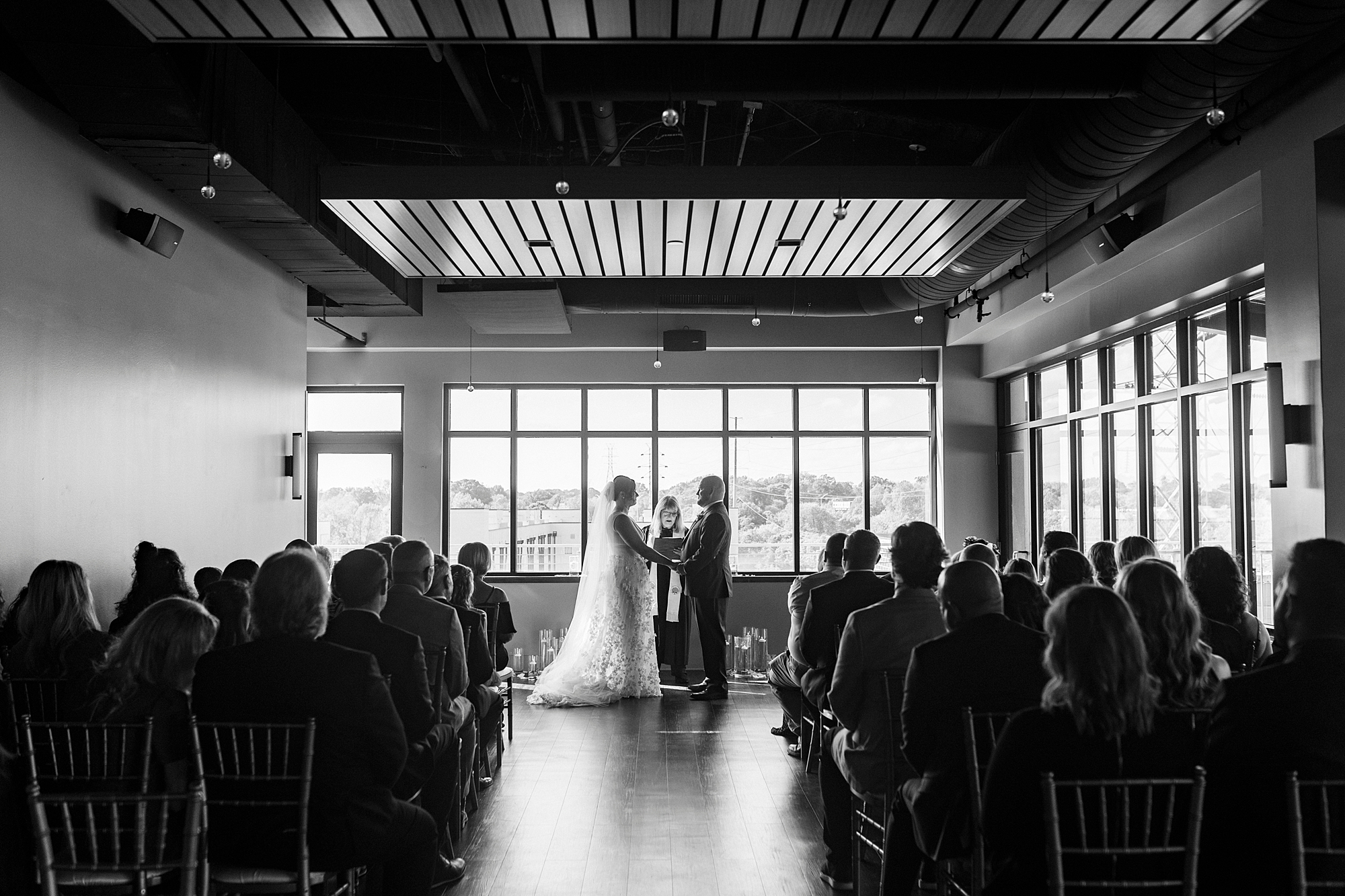 bride and groom hold hands near window inside the Terrace at Cedar Hill for wedding ceremony