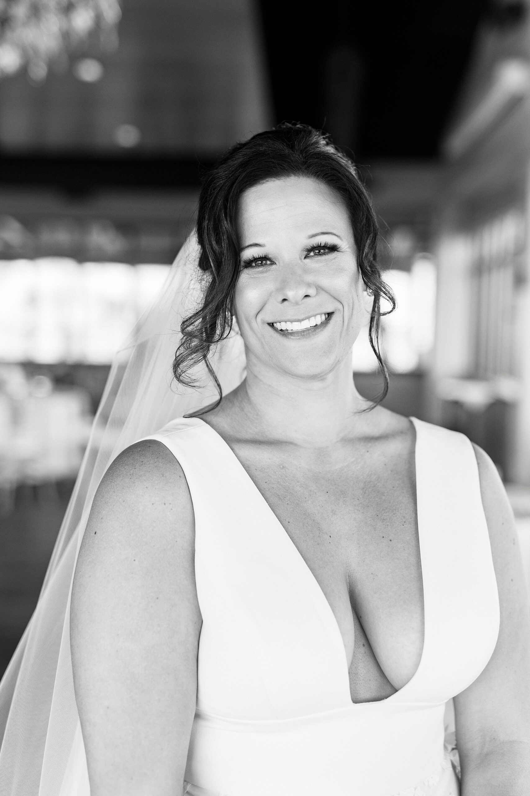 black and white photo of bride smiling in wedding dress with v-bodice