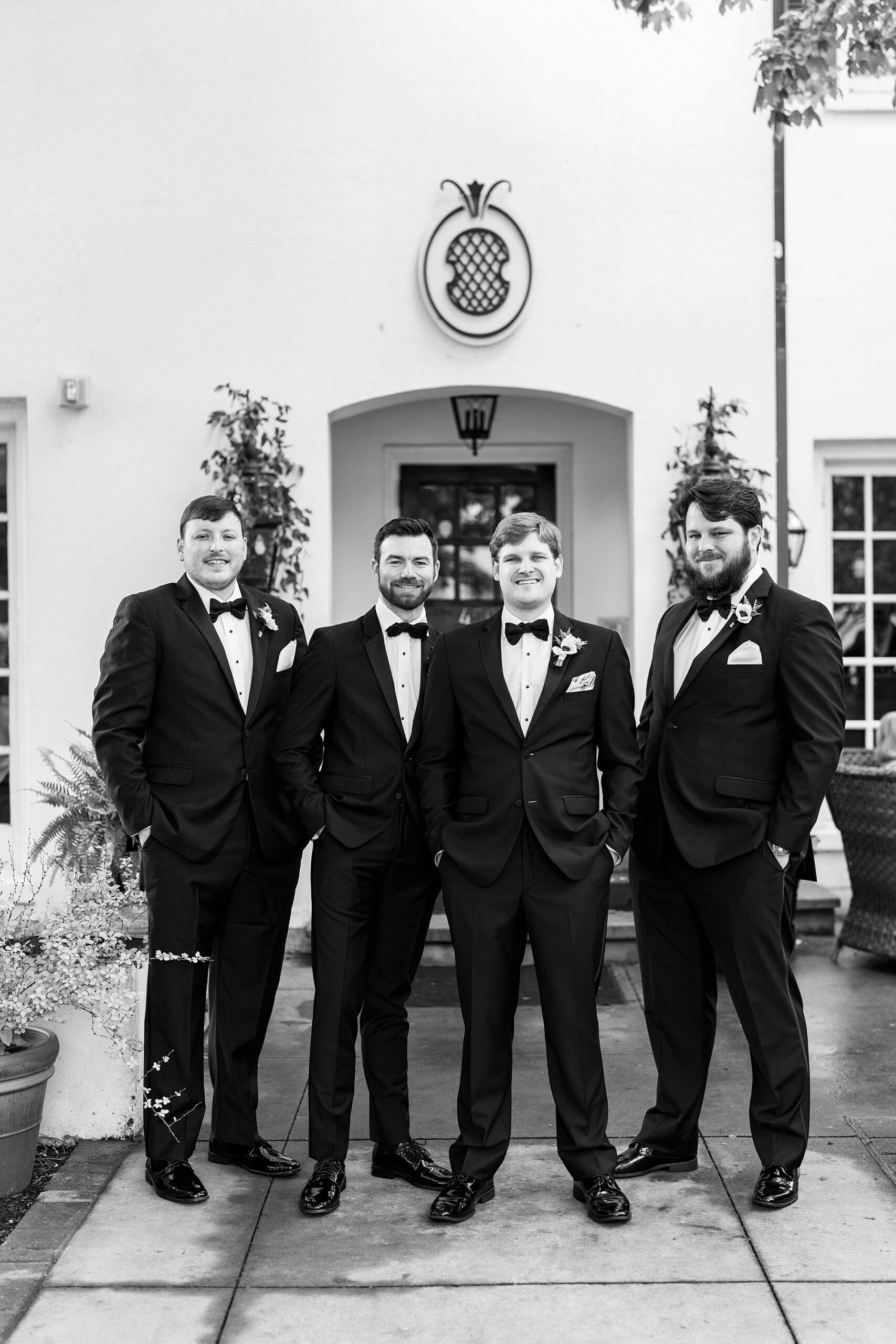 groom stands with groomsmen in black suits at The Spring House