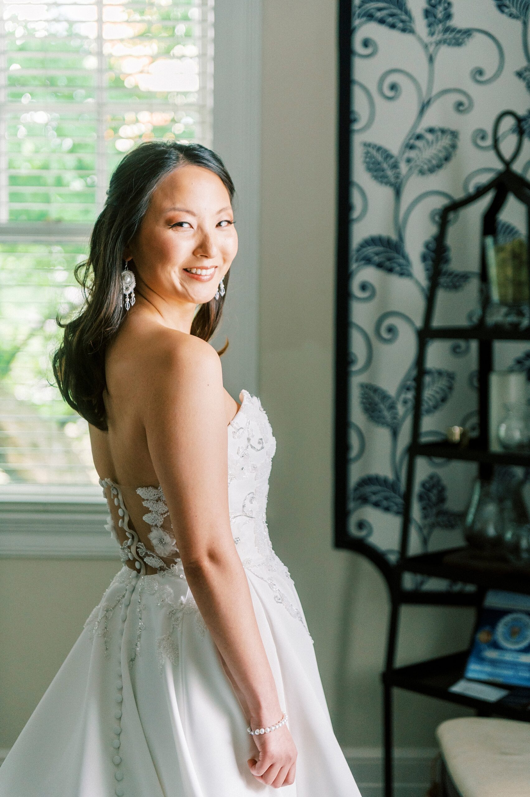 bride looks over shoulder in strapless gown smiling in bridal suite at The Spring House