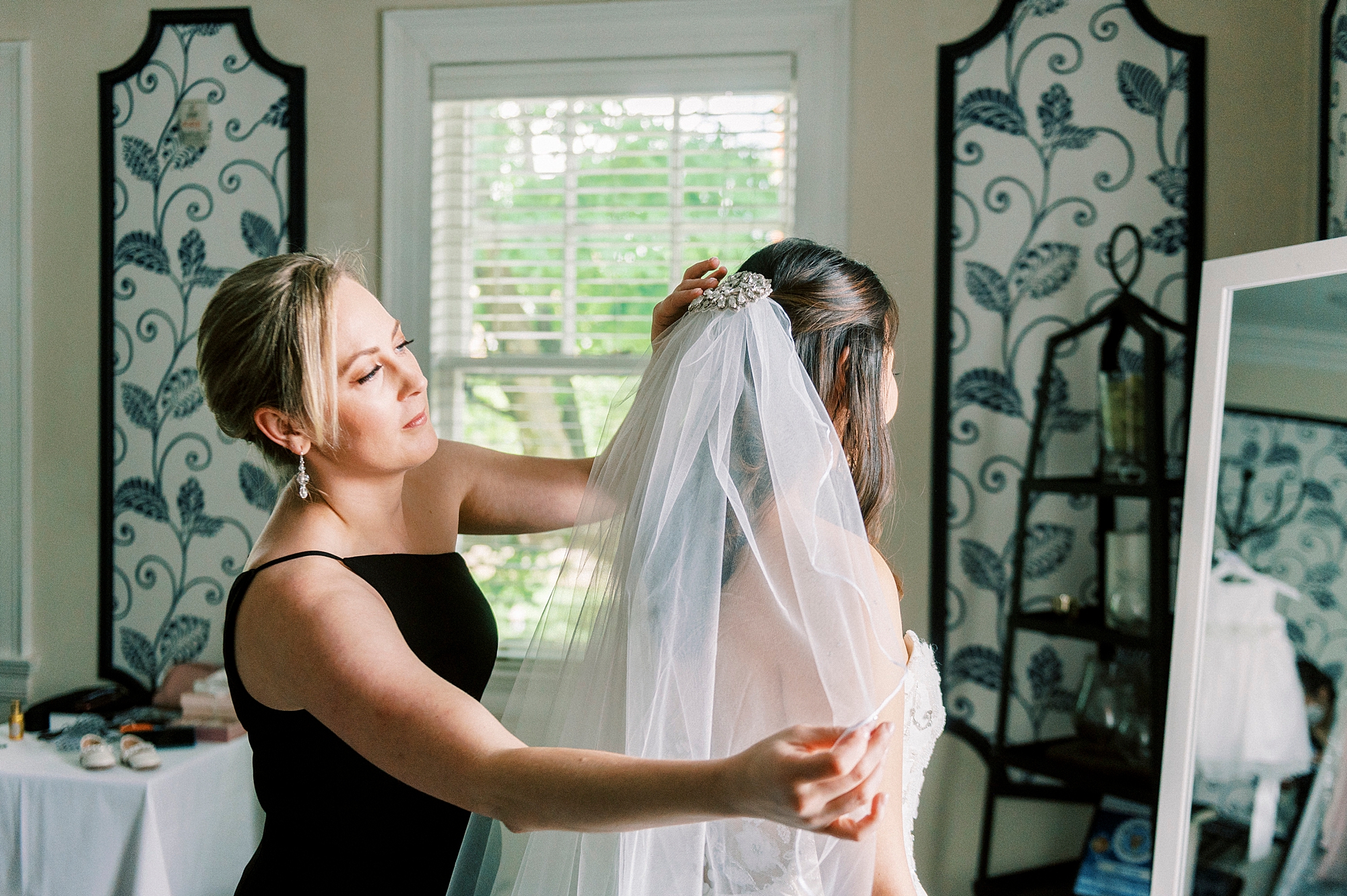 mother helps bride with veil looking in mirror in suite at The Spring House