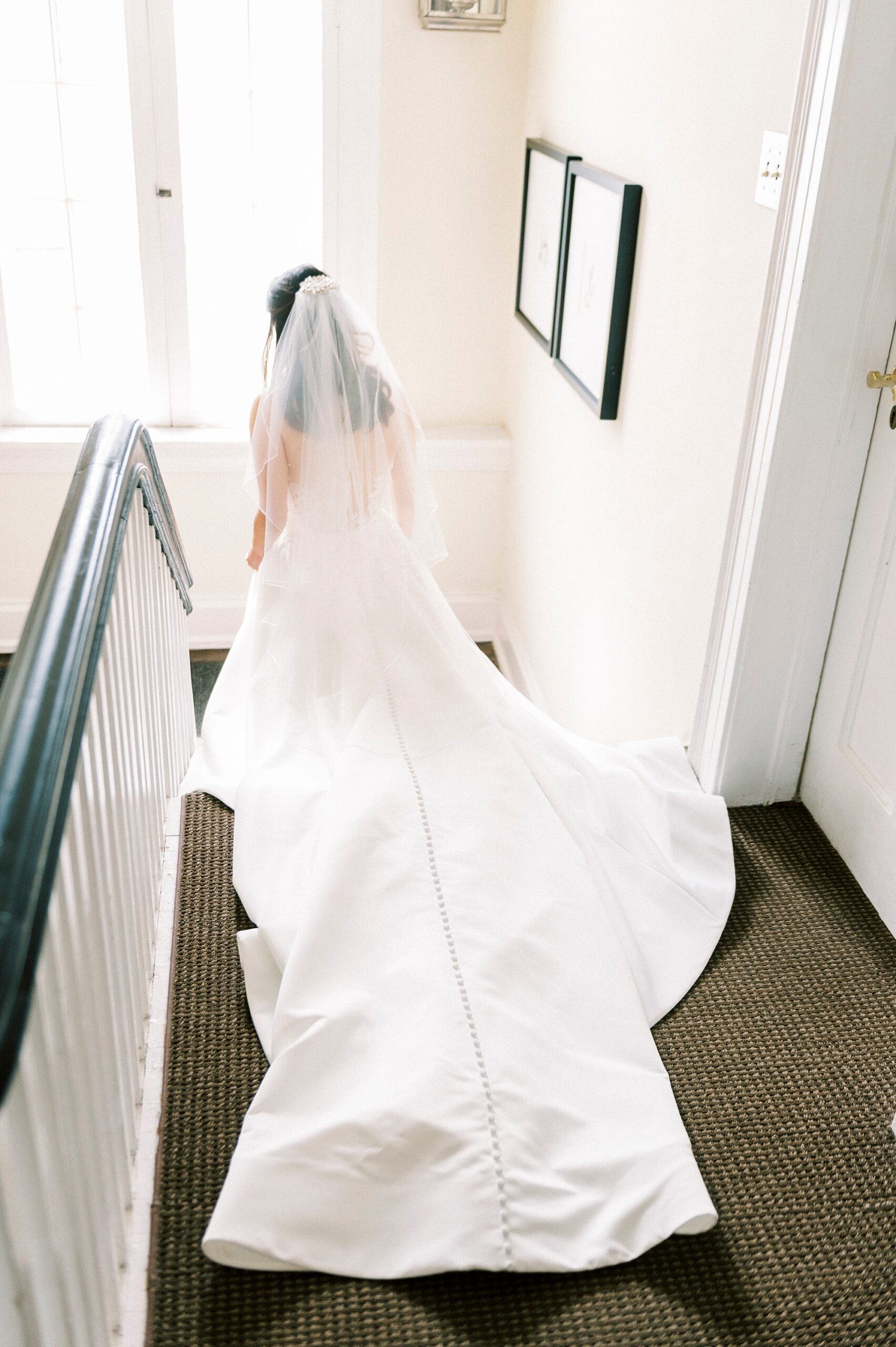 bride walks down steps with wedding dress trailing behind her 