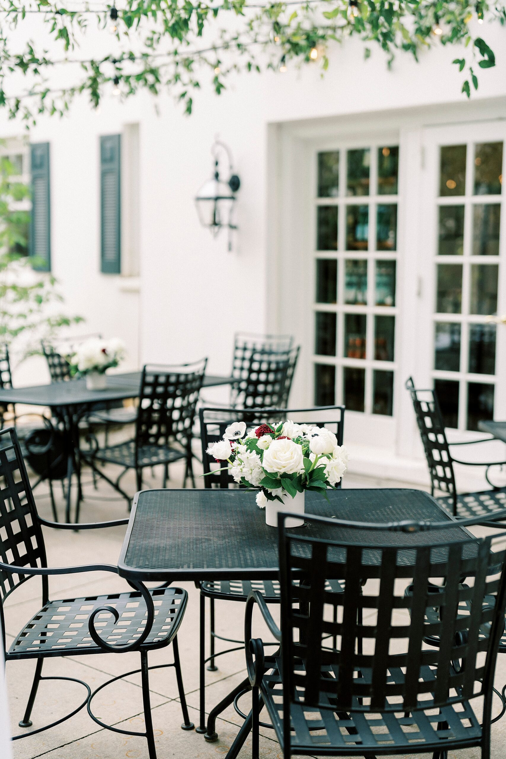 patio with white flowers on black wrought iron tables at The Spring House