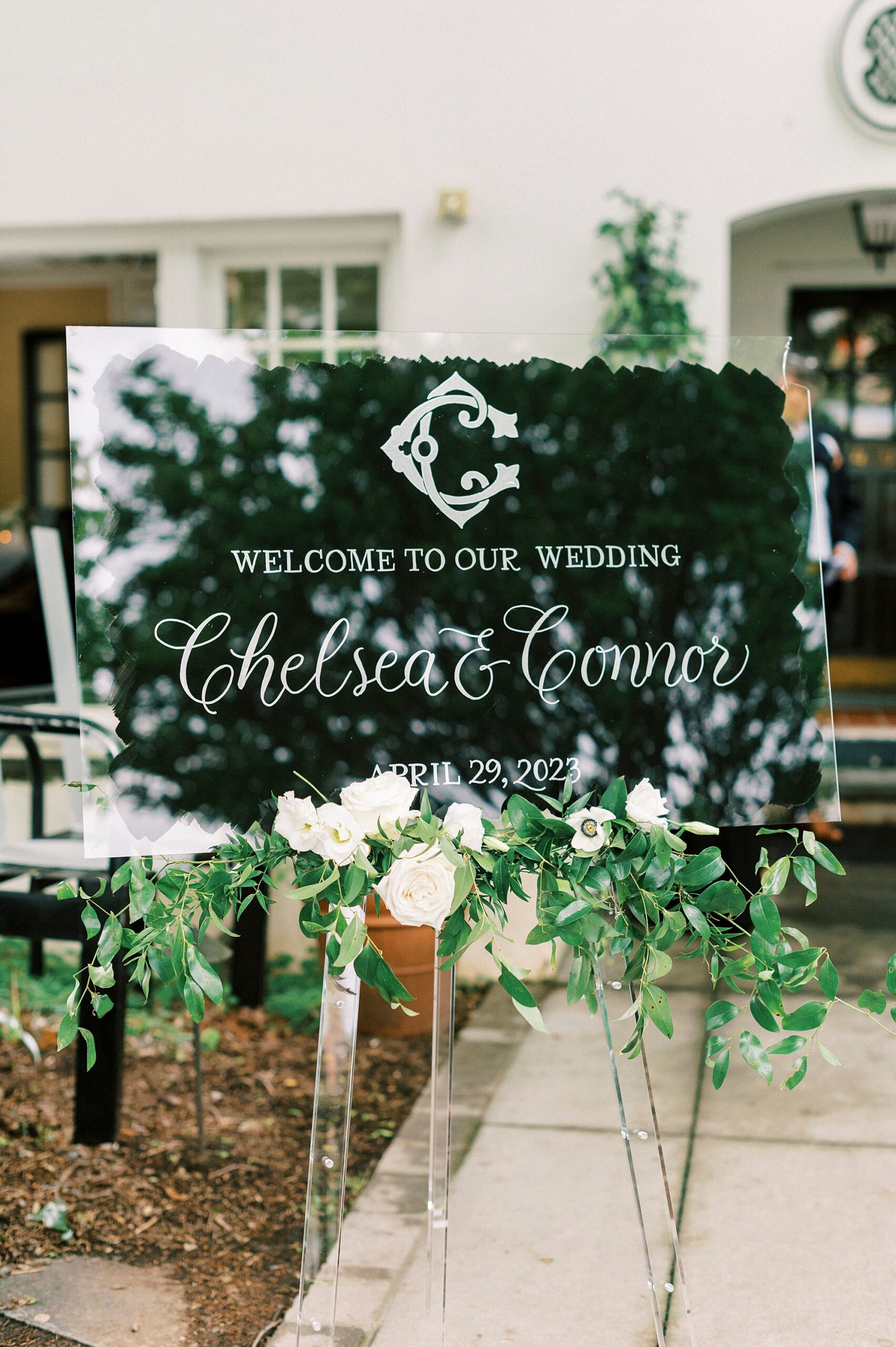 welcome sign on acrylic sheet above greenery 