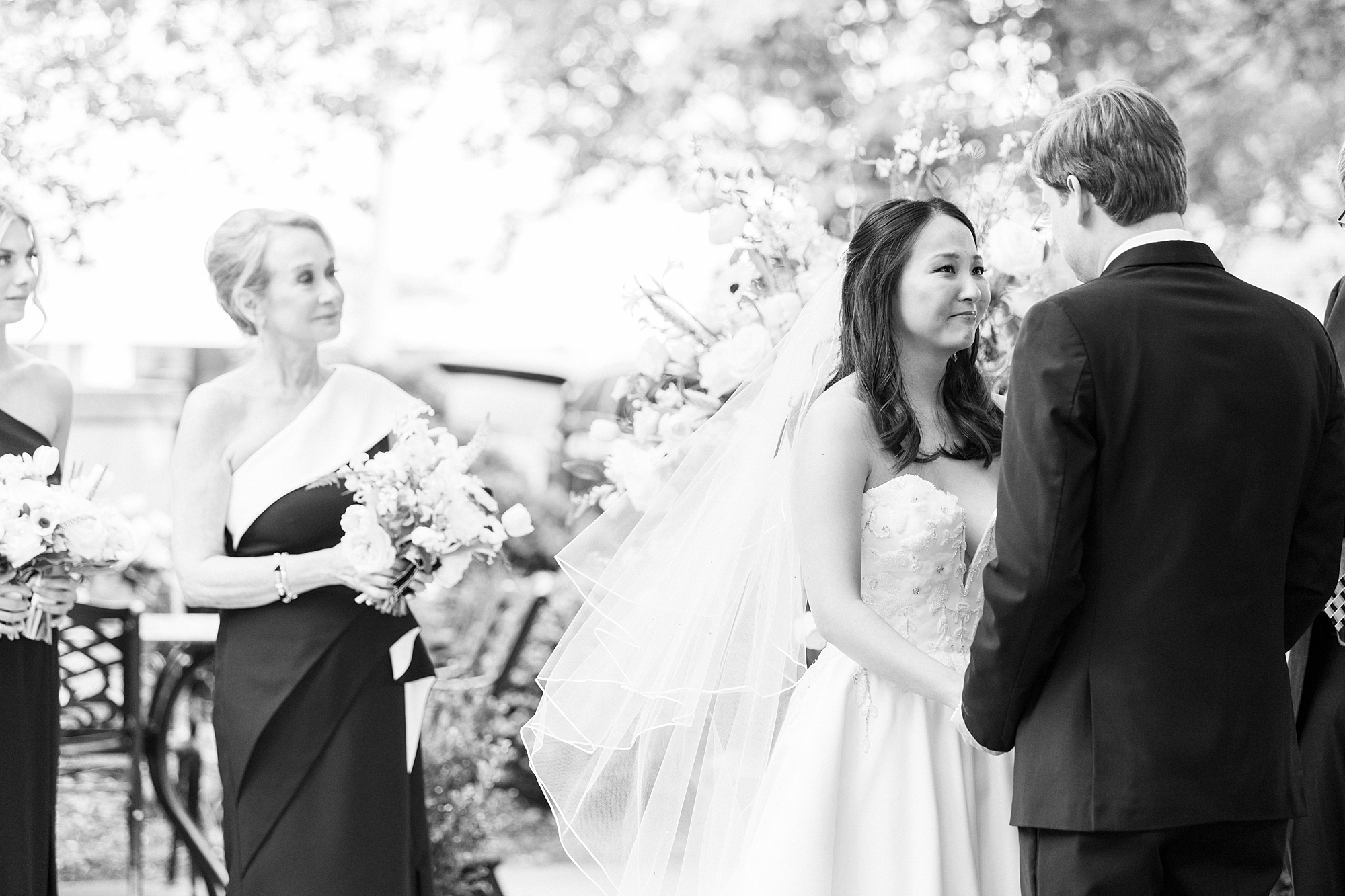 bride and groom smile at each other holding hands during wedding ceremony 