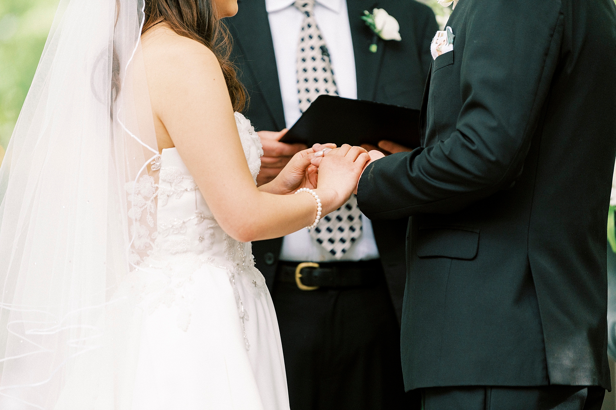 bride and groom hold hands during wedding ceremony 