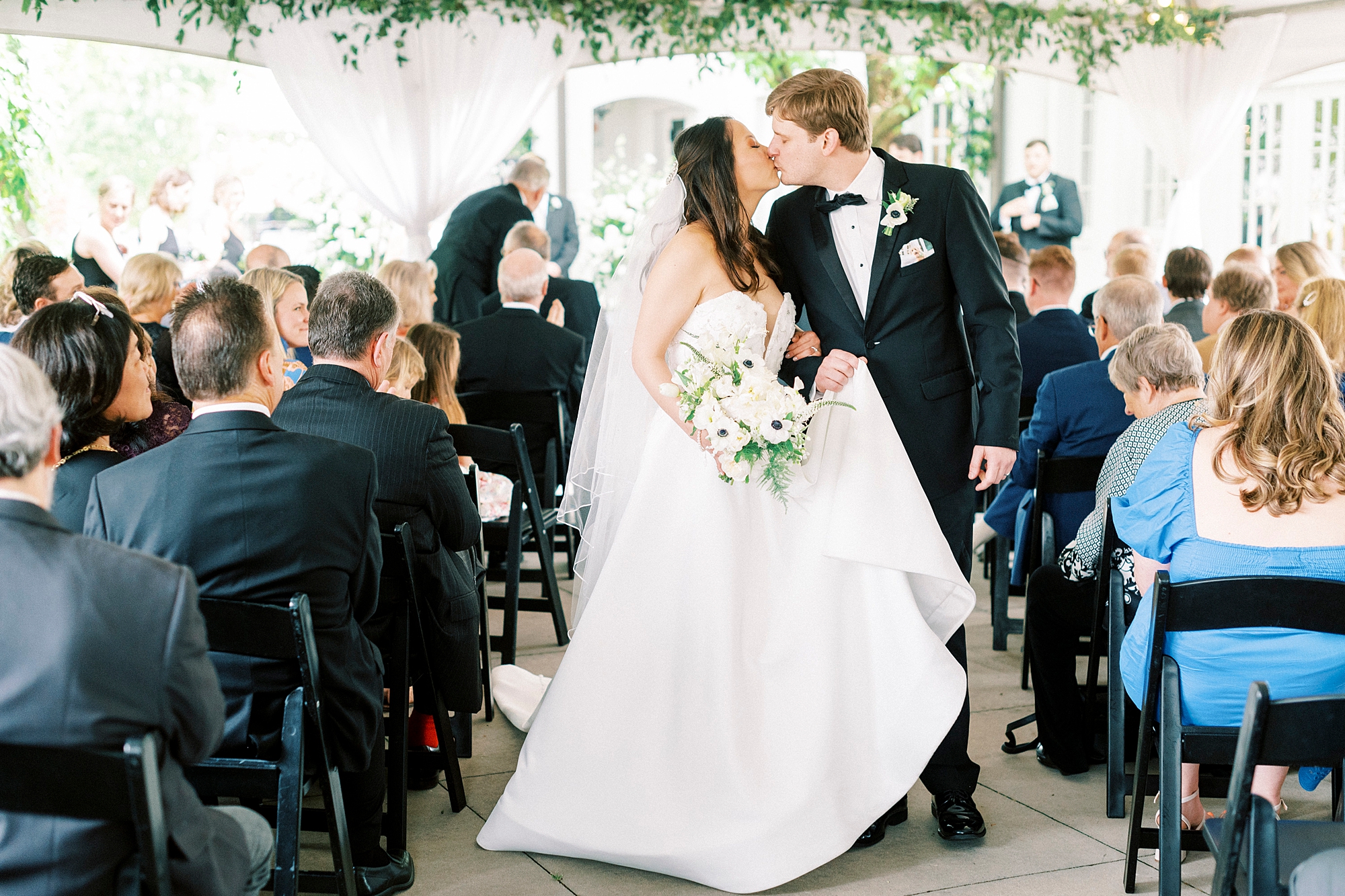 bride and groom kiss in aisle during wedding ceremony at The Spring House