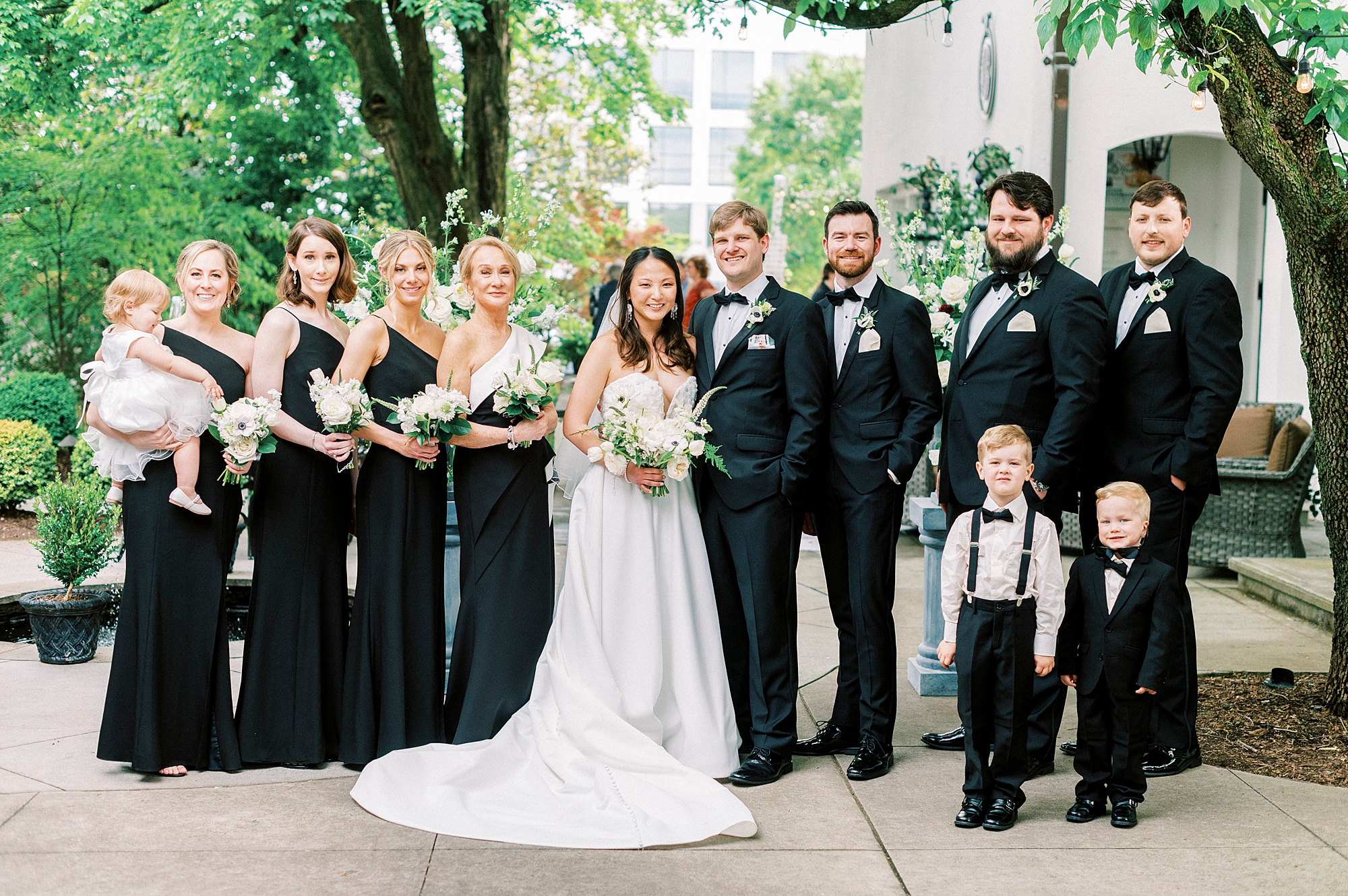 bride and groom pose with wedding party in black attire 