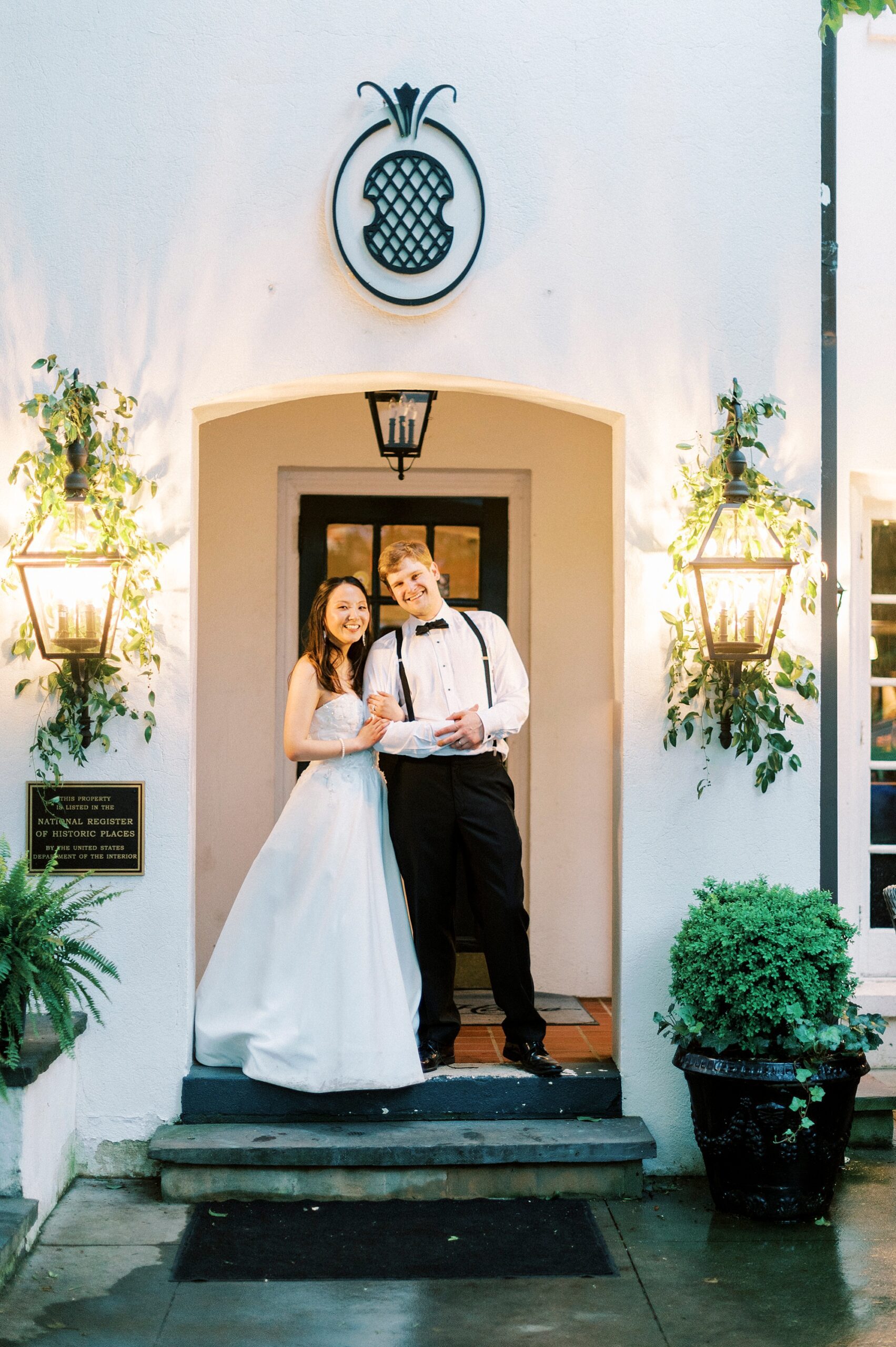 bride and groom stand on steps outside The Spring House