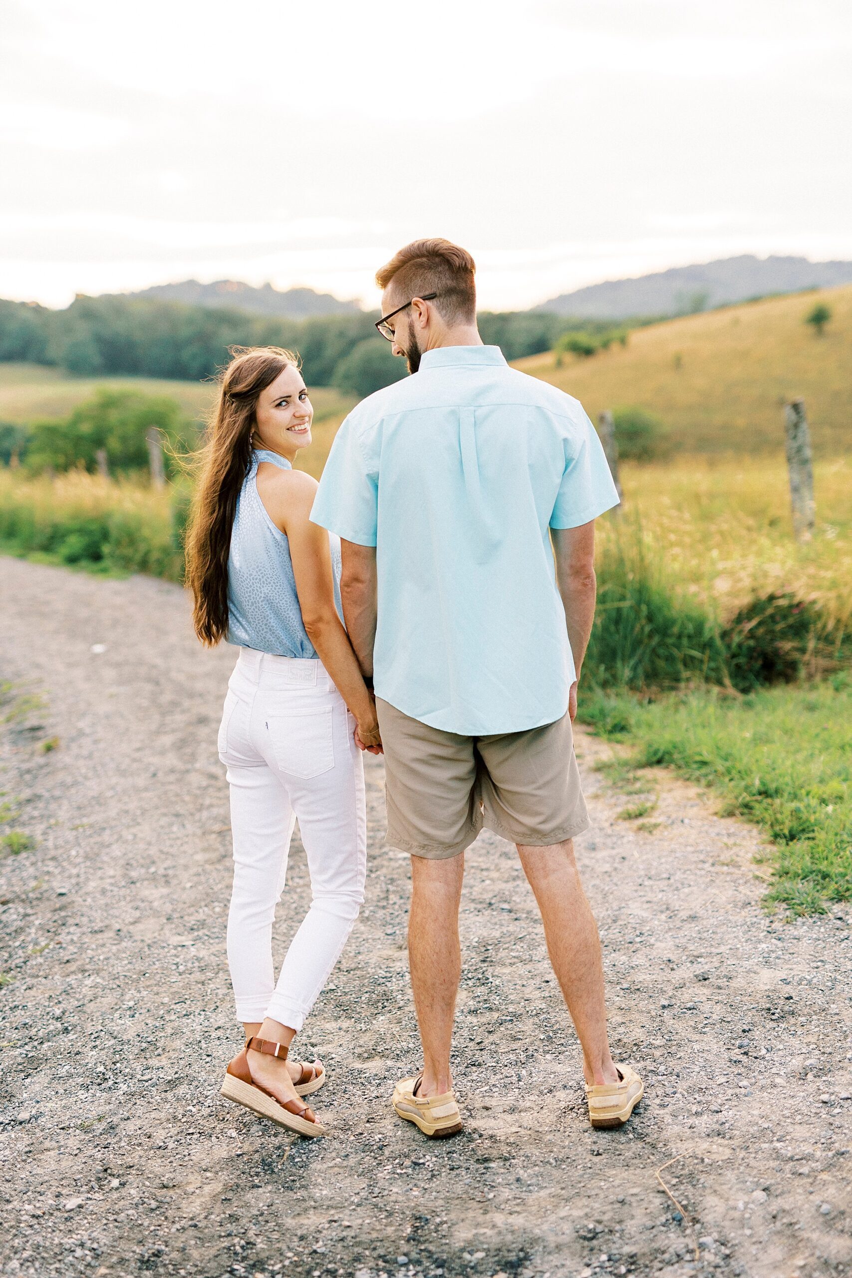couple holds hands while woman looks over shoulder during Blue Ridge Parkway engagement session