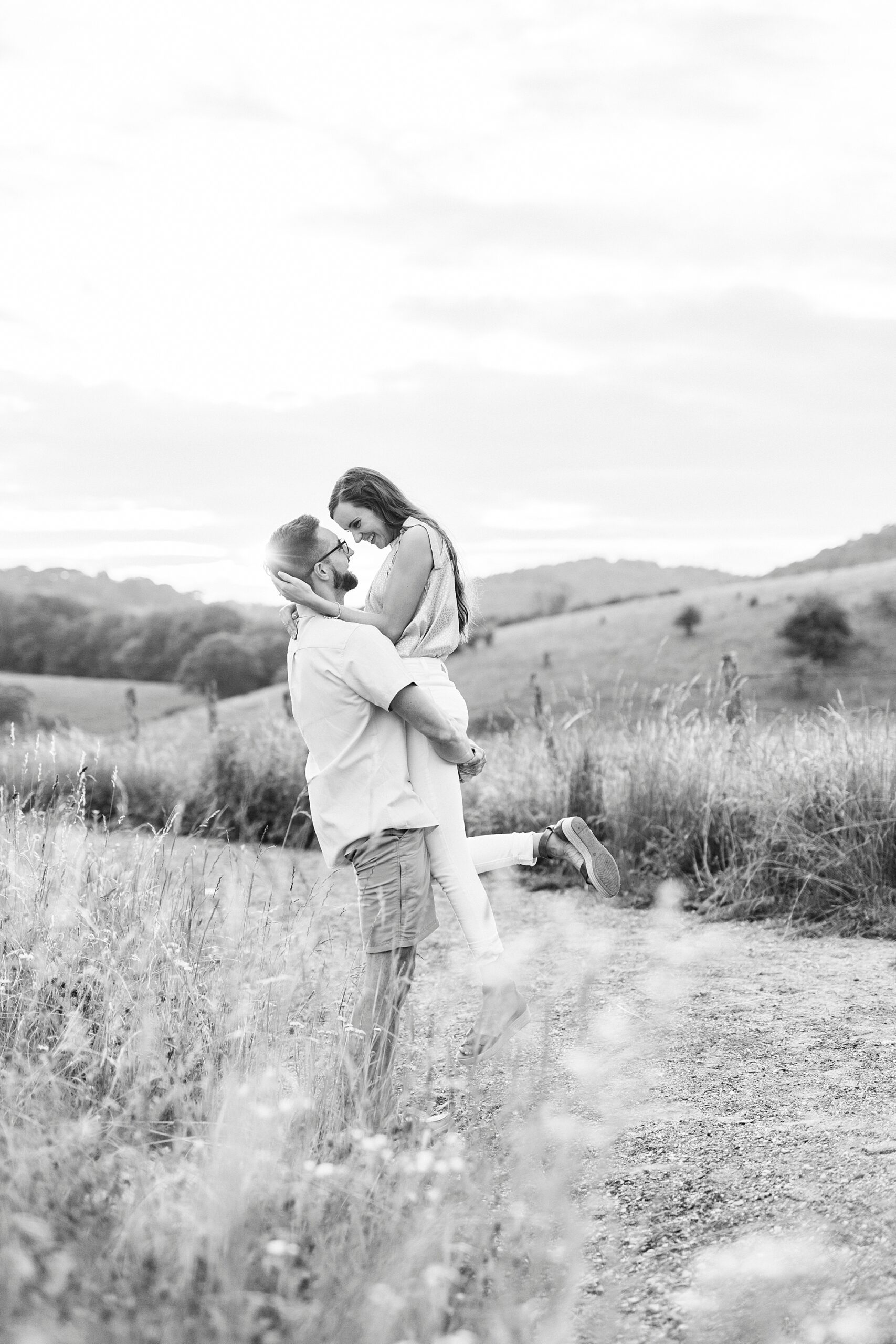 man lifts up bride during Blue Ridge Parkway engagement session at Moses Cone Manor