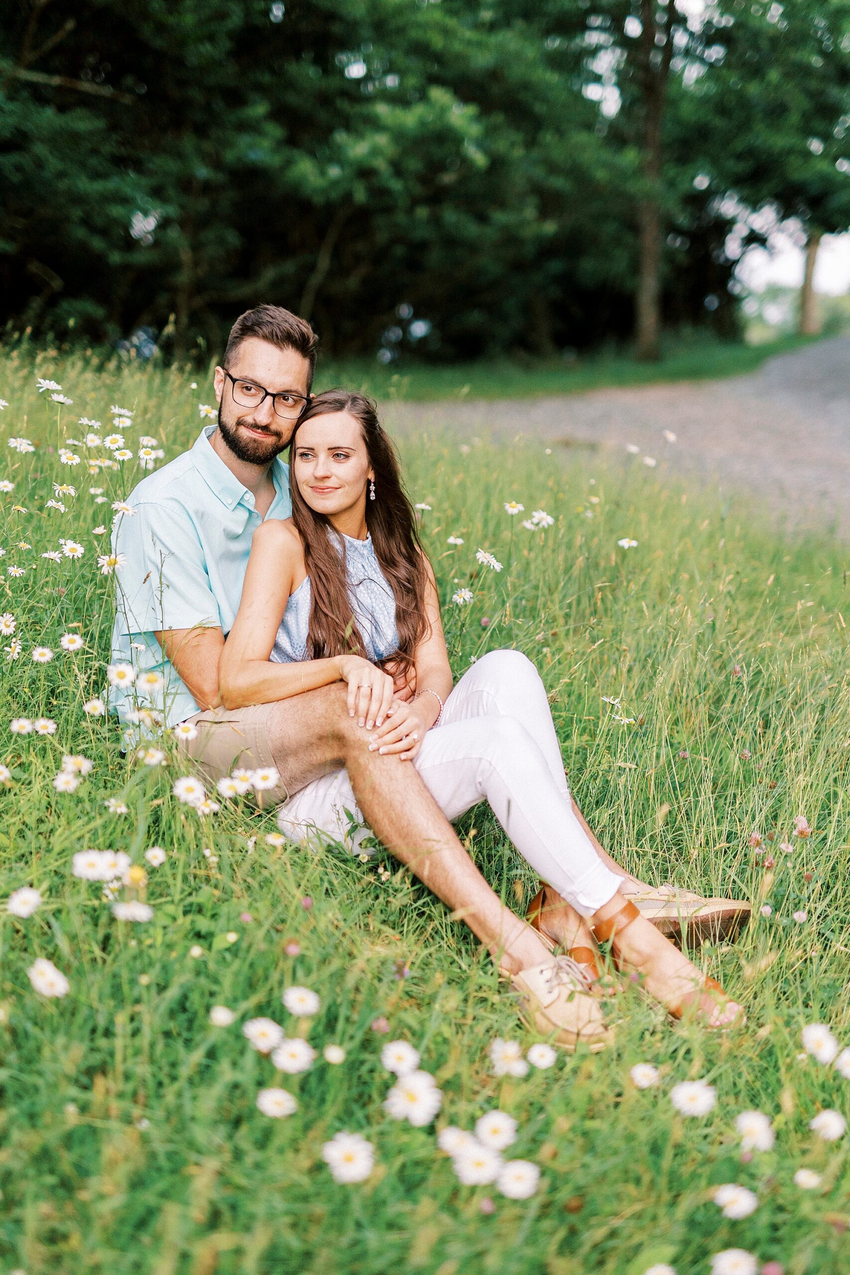 woman sits in front of man on hill with wildflowers at Moses Cone Manor