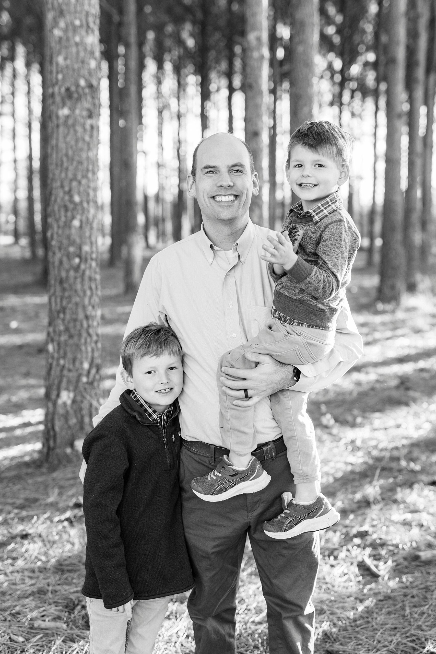 dad stand holding two sons during family photos at Frank Liske Park