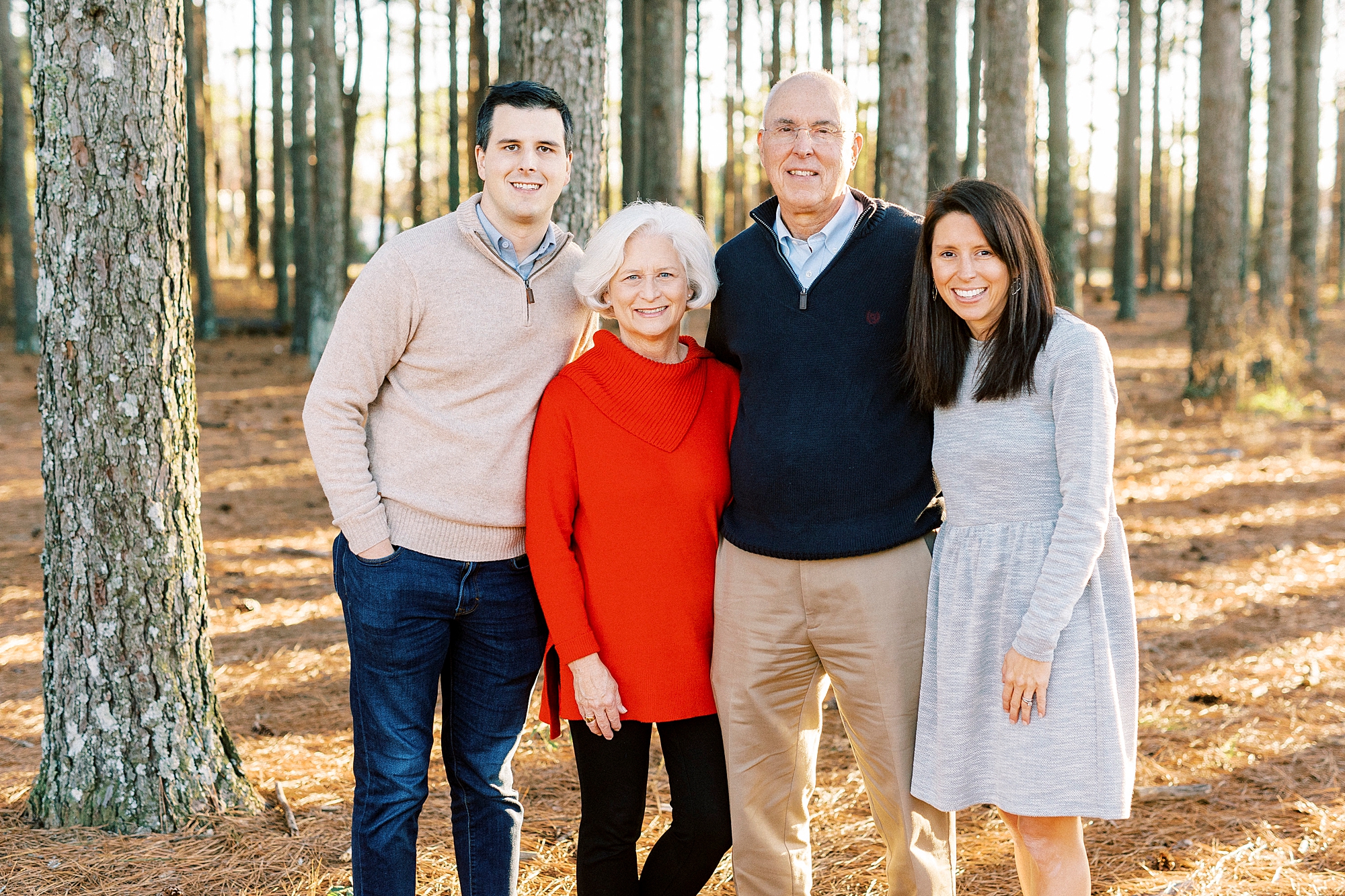 couple poses with parents during family portraits in the fall 