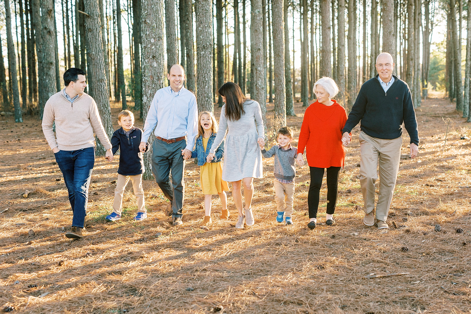 family holds hands walking in woods during portraits at Frank Liske Park