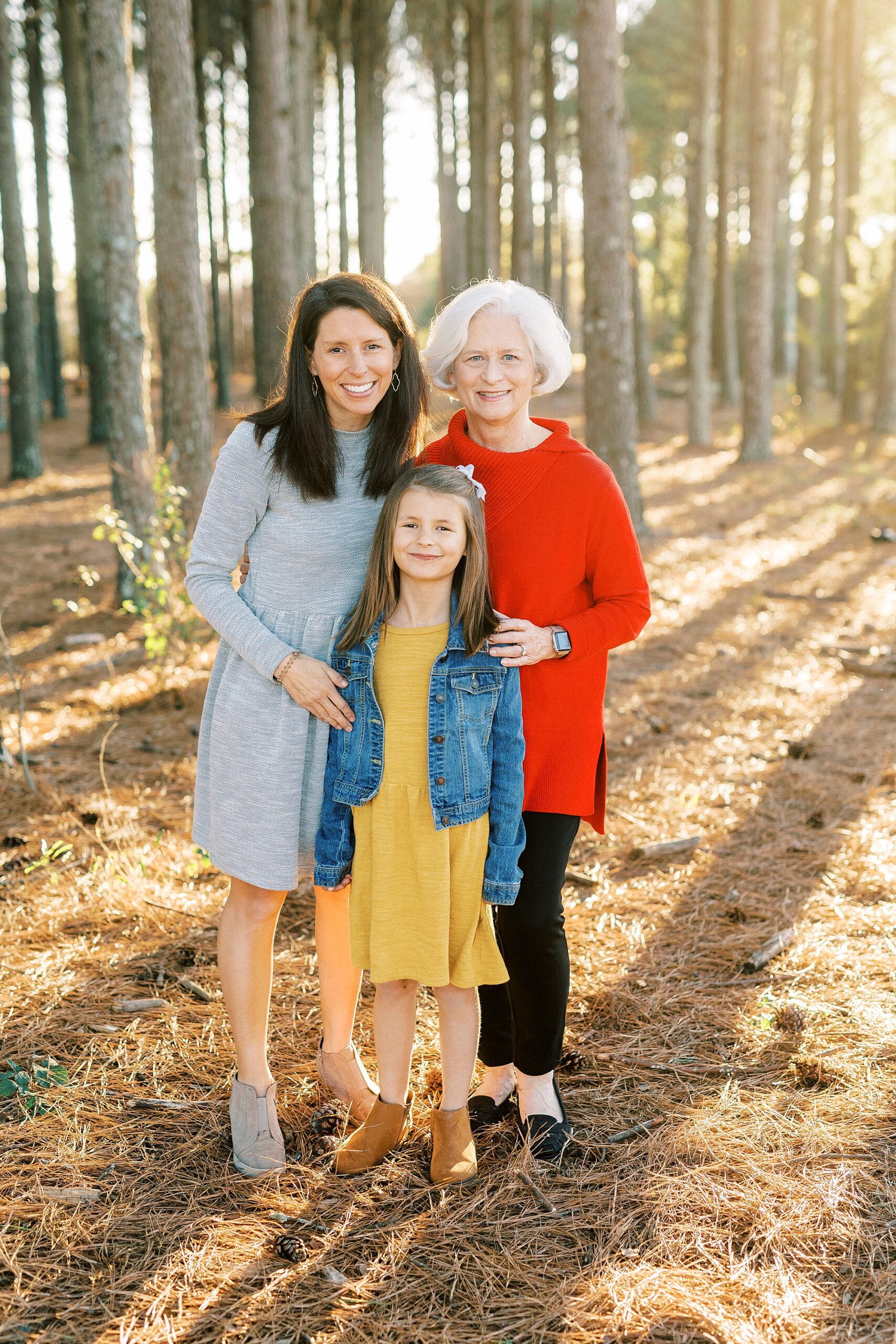 mom and grandmother pose with girl in blue jean jacket and yellow dress