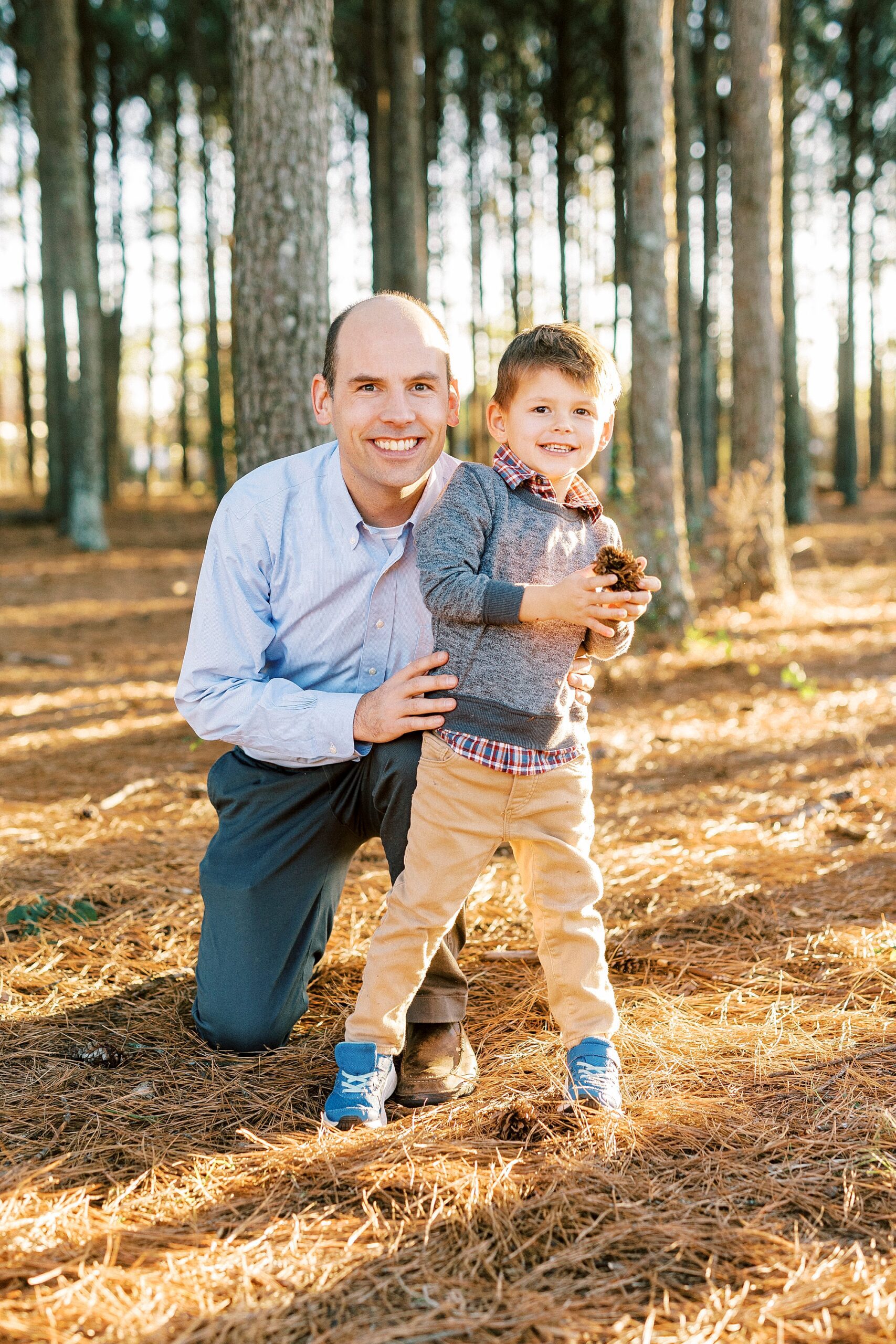 dad kneels with young son on edge of woods at Frank Liske Park