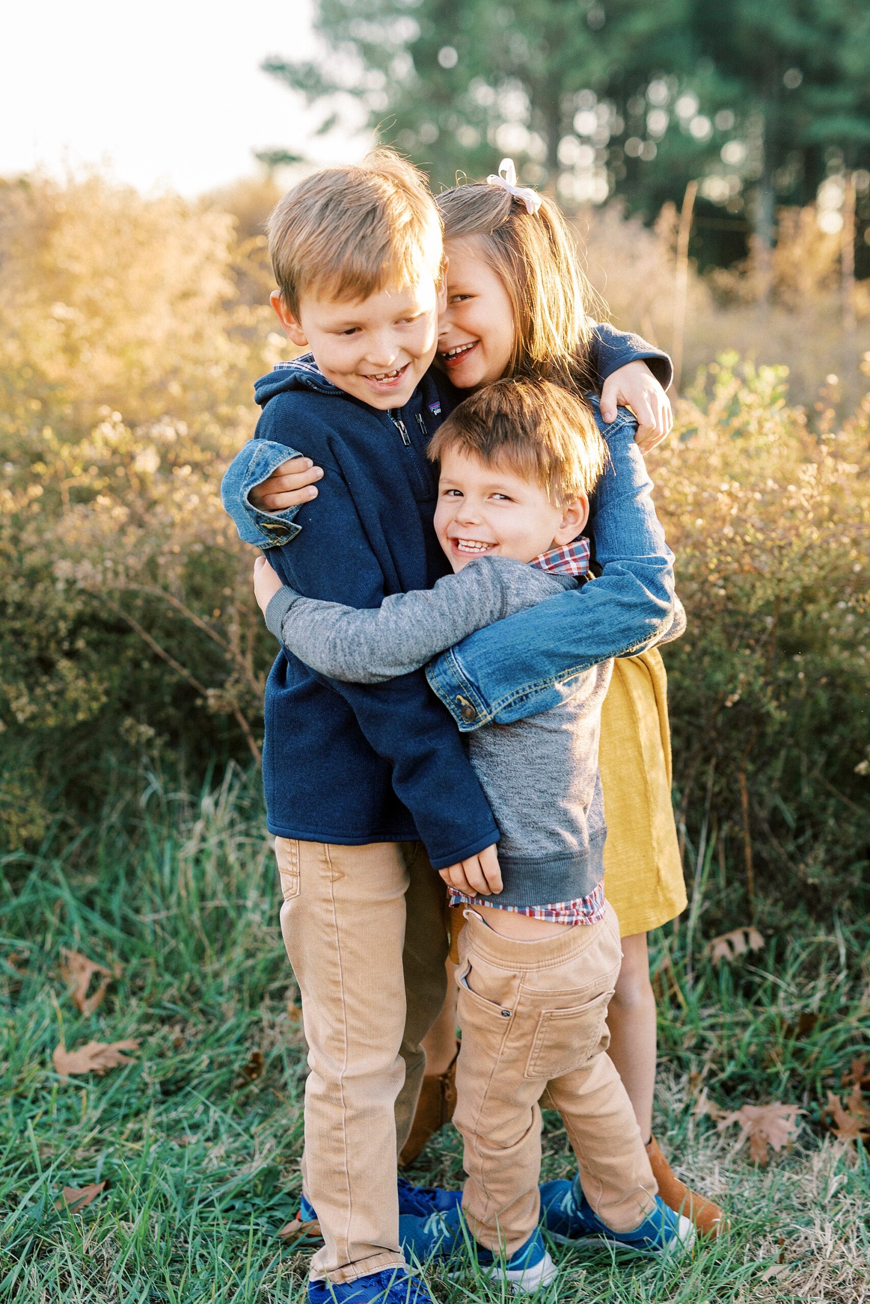three siblings hug near edge of field at Frank Liske Park