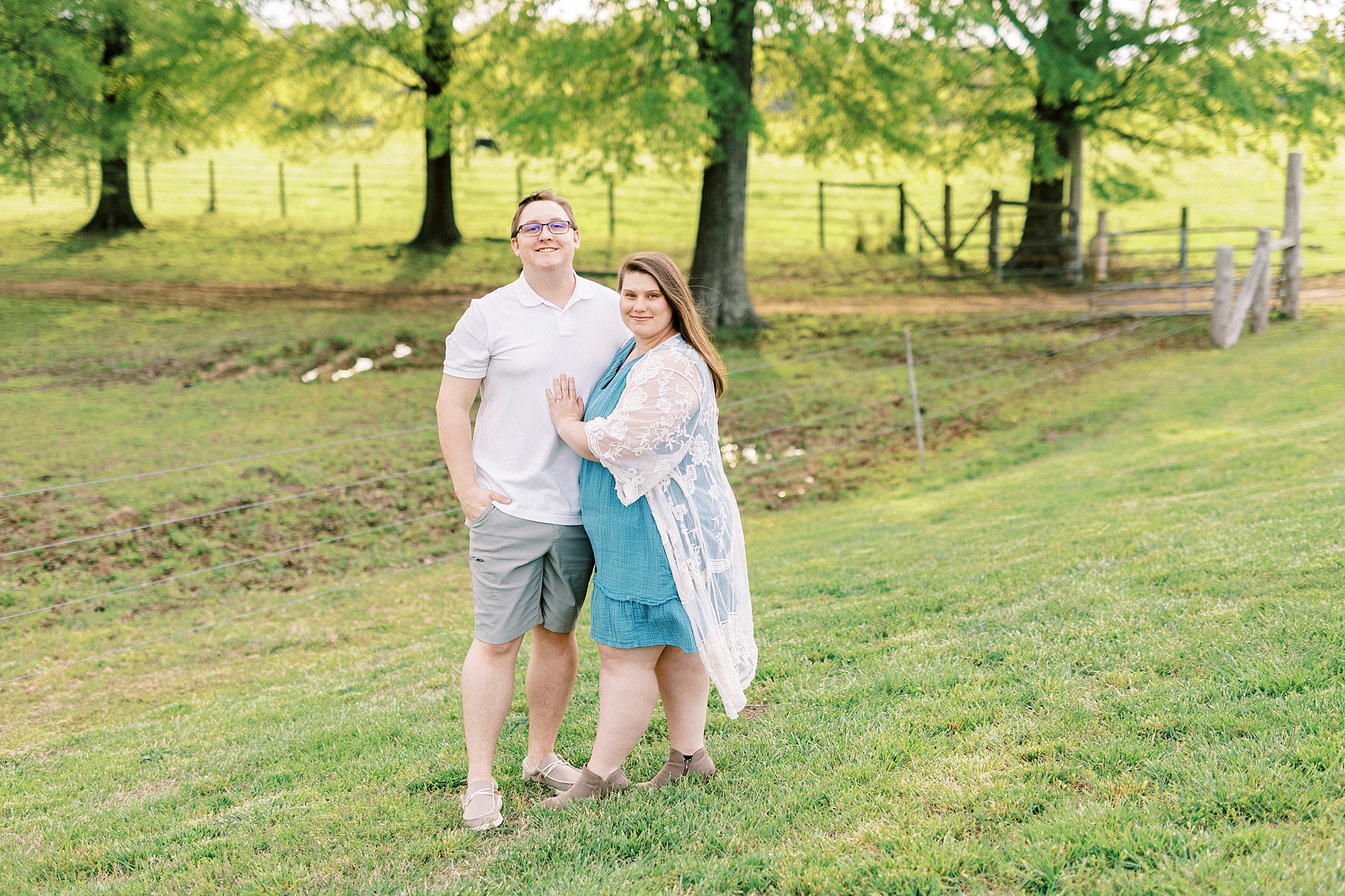 woman in blue dress with white lace wrap hugs man on lawn at the Farmstead