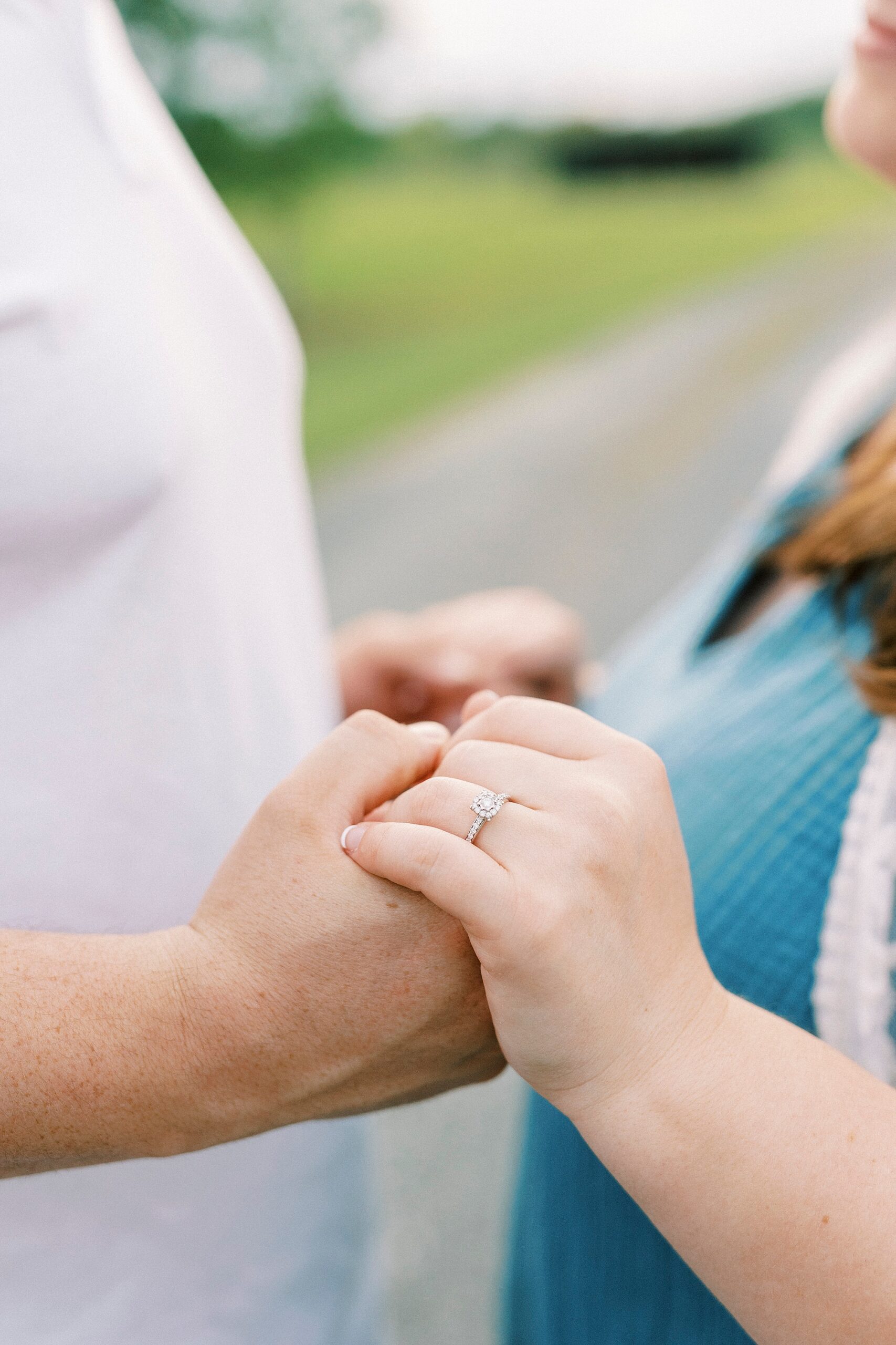 man holds woman's hand showing off engagement ring