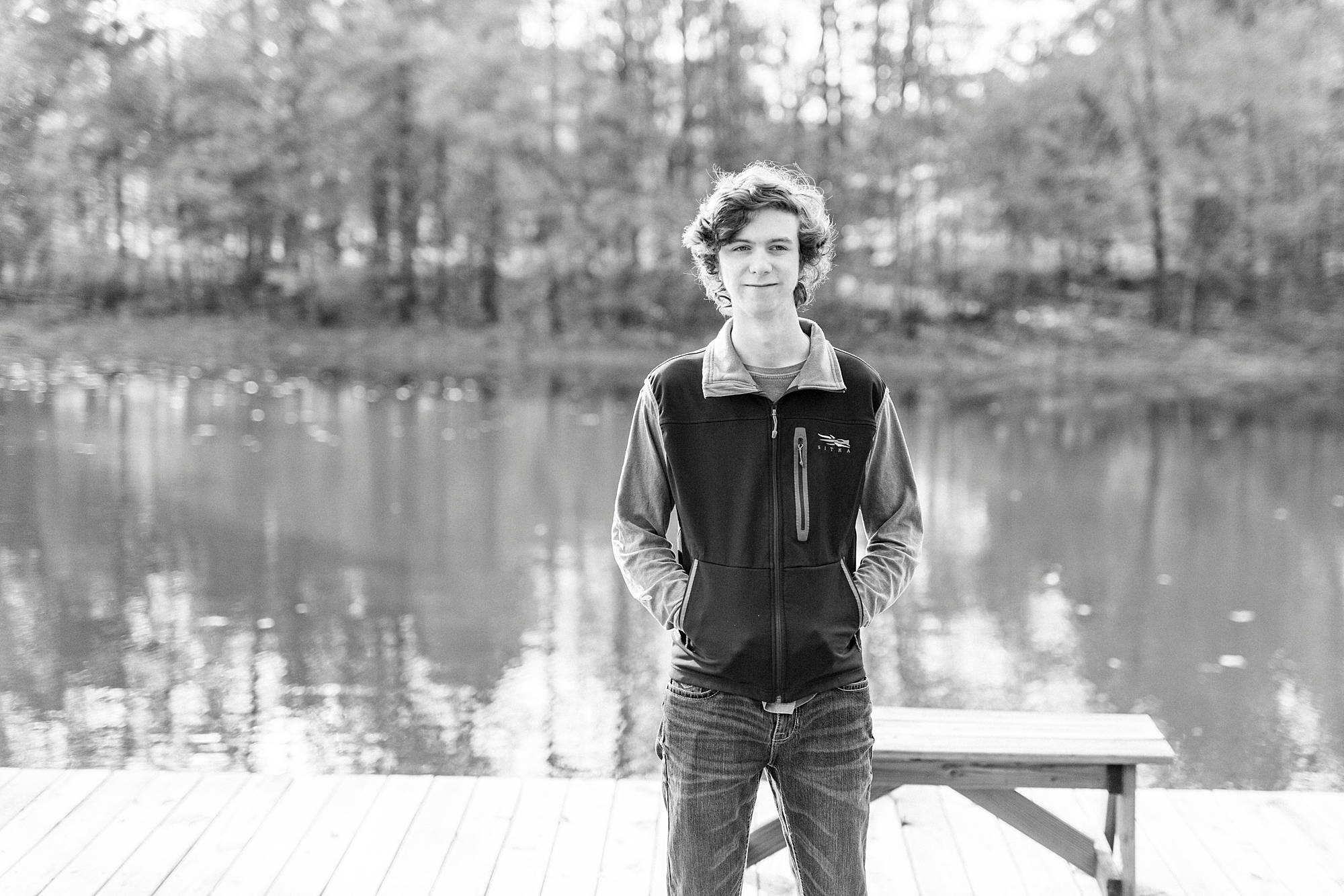 senior boy stands by lake in Midland NC