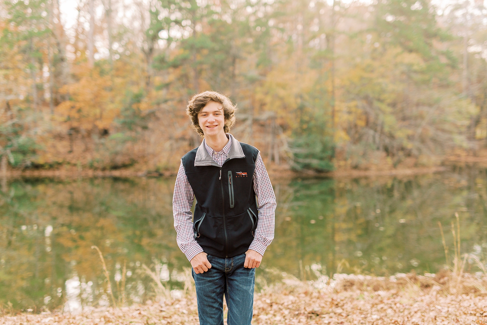 senior guy stands with hands in pockets of jeans during fall photos in Midland NC