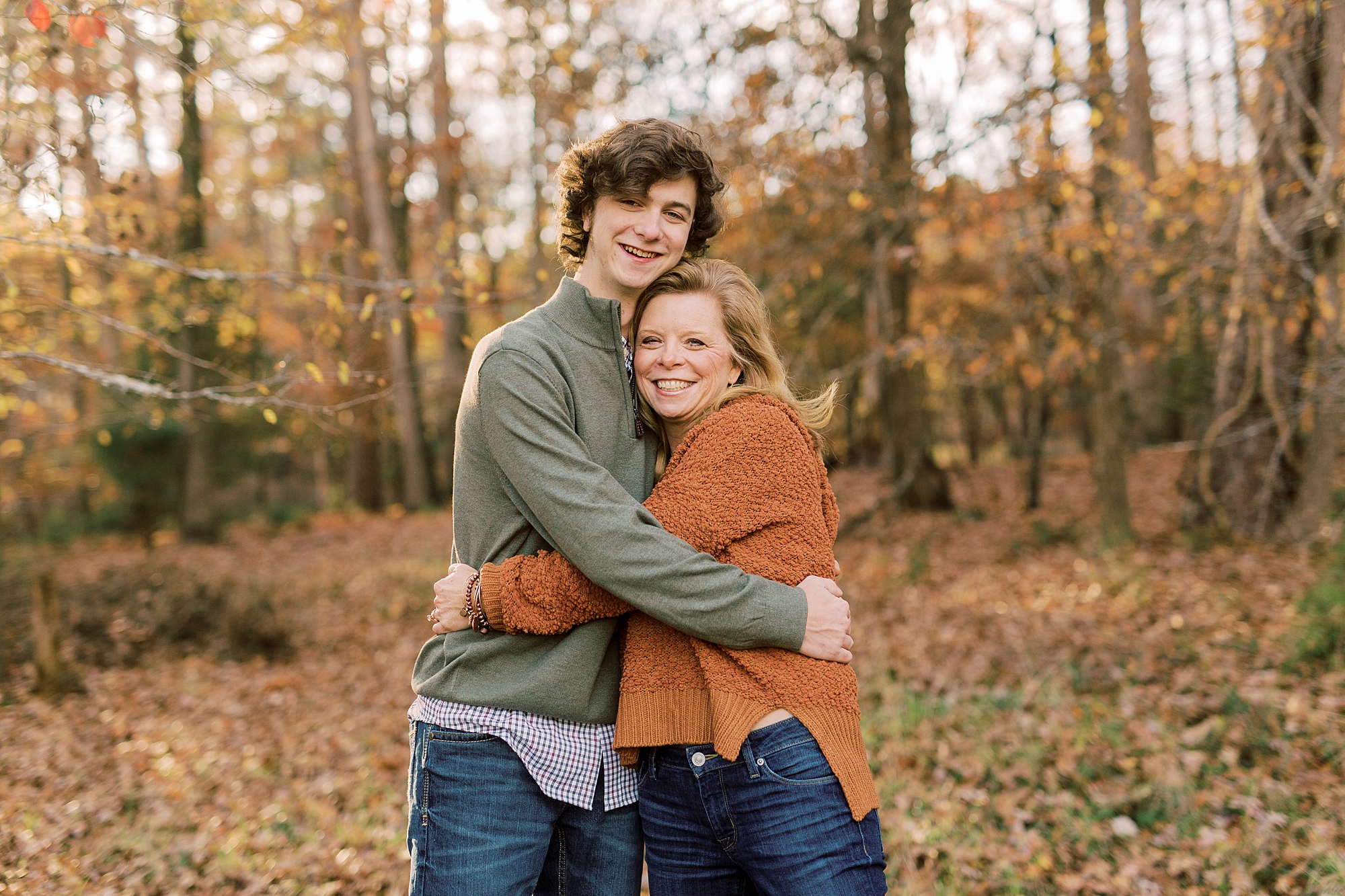senior boy hugs mom in orange sweater during fall senior photos in Midland NC