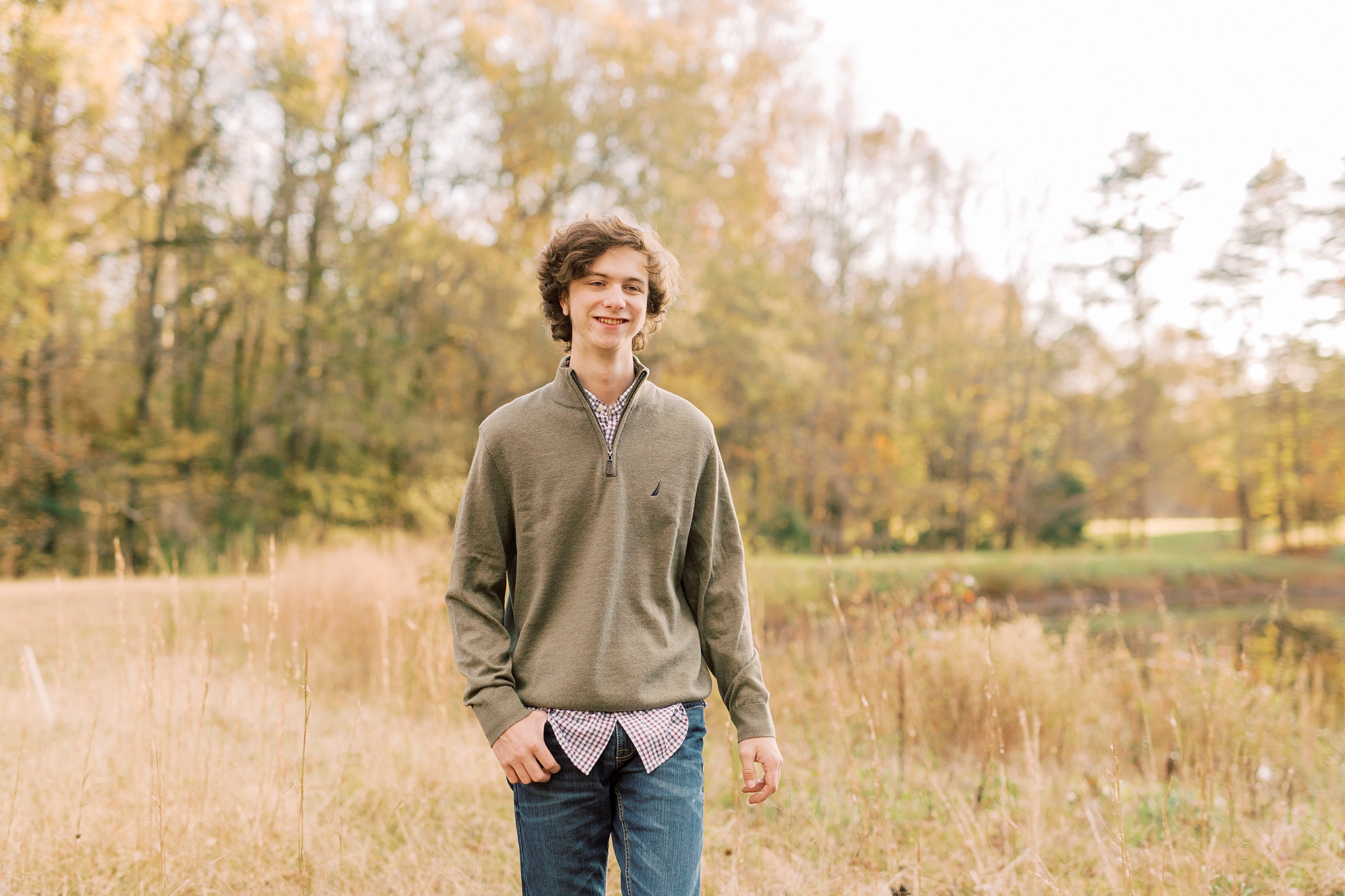 senior boy walks through grass during all portraits in Midland NC