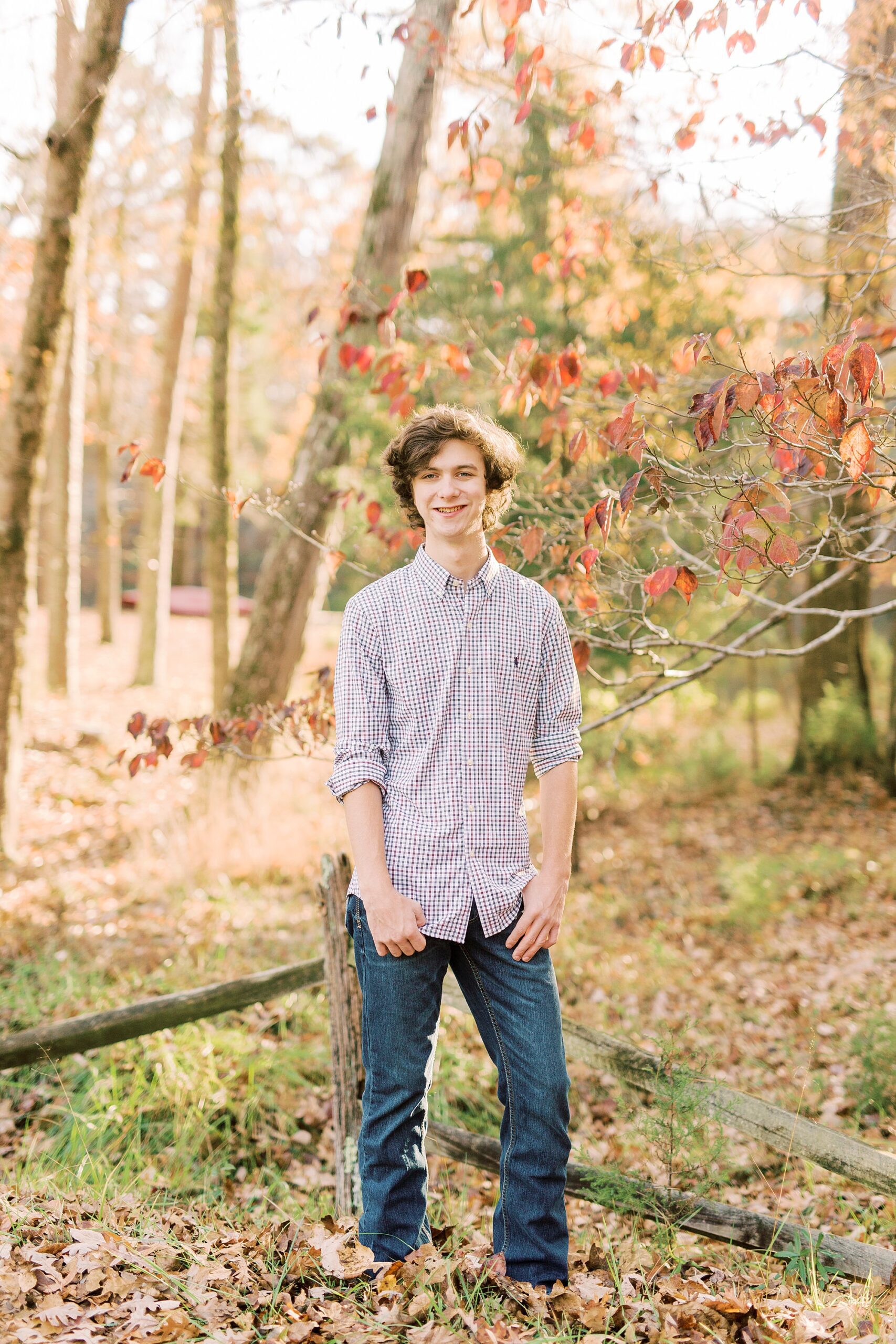 boy stands among leaves in the fall during Midland NC senior portraits 