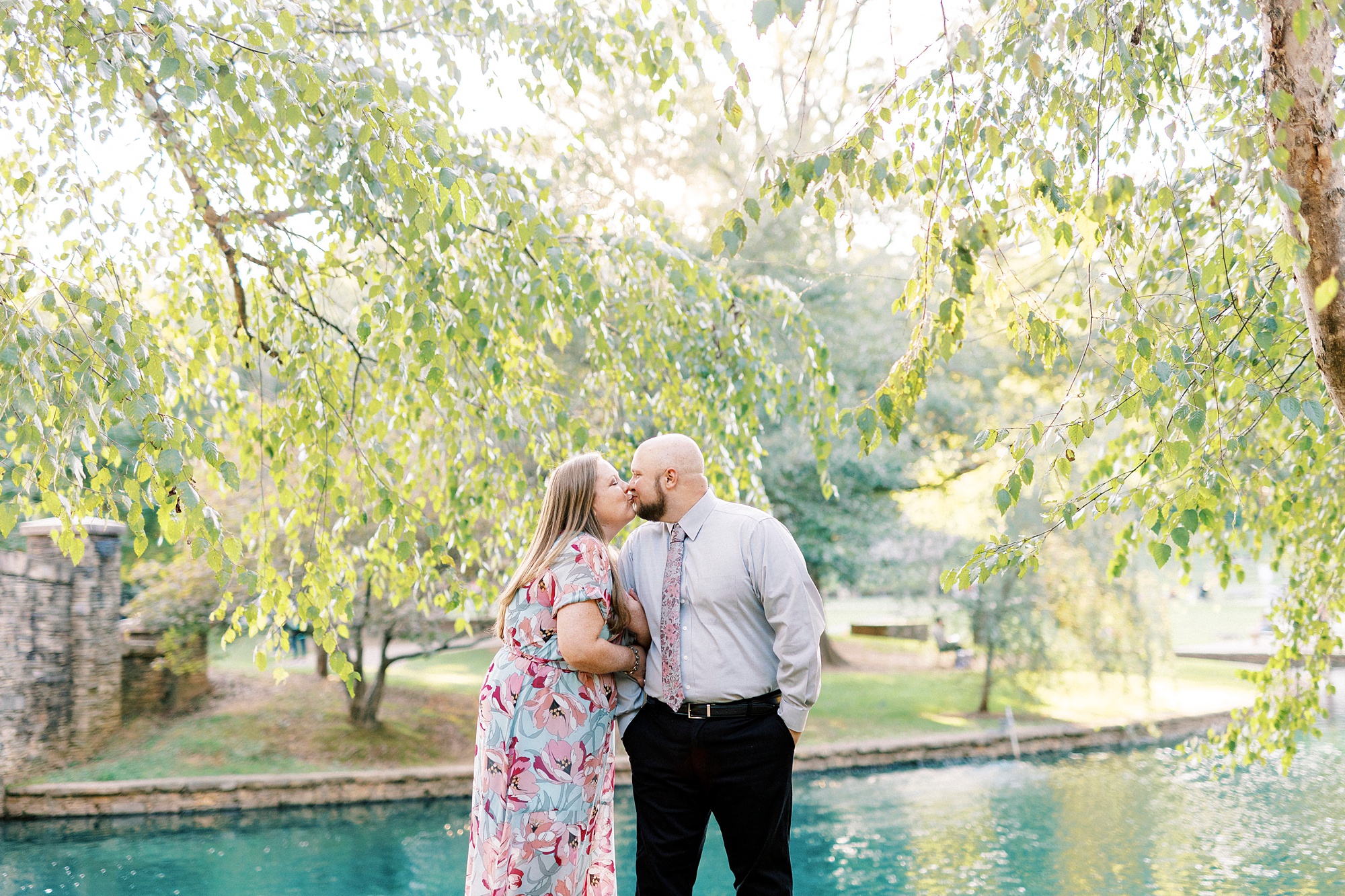 engaged couple kisses under weeping willow during Freedom Park engagement portraits