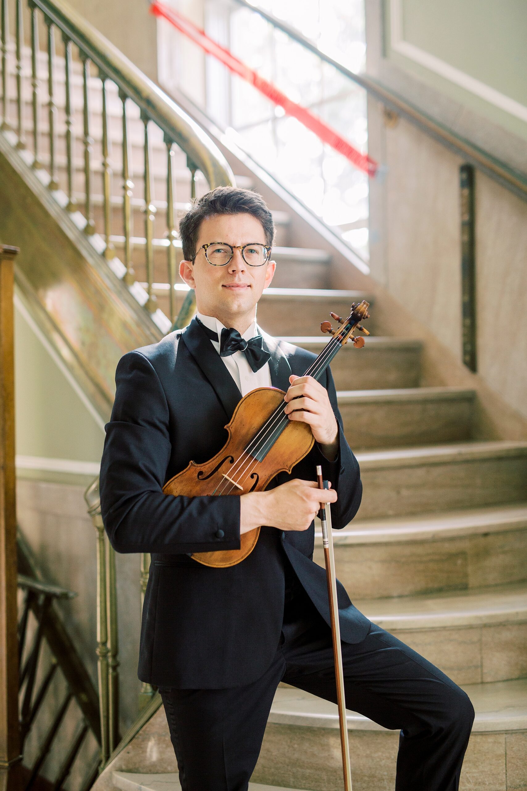 violin player stands near staircase during SC headshots 