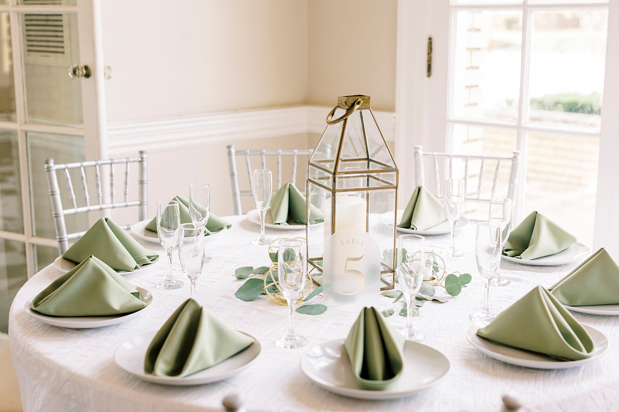 reception place setting with sage green napkins and gold lantern at Separk Mansion