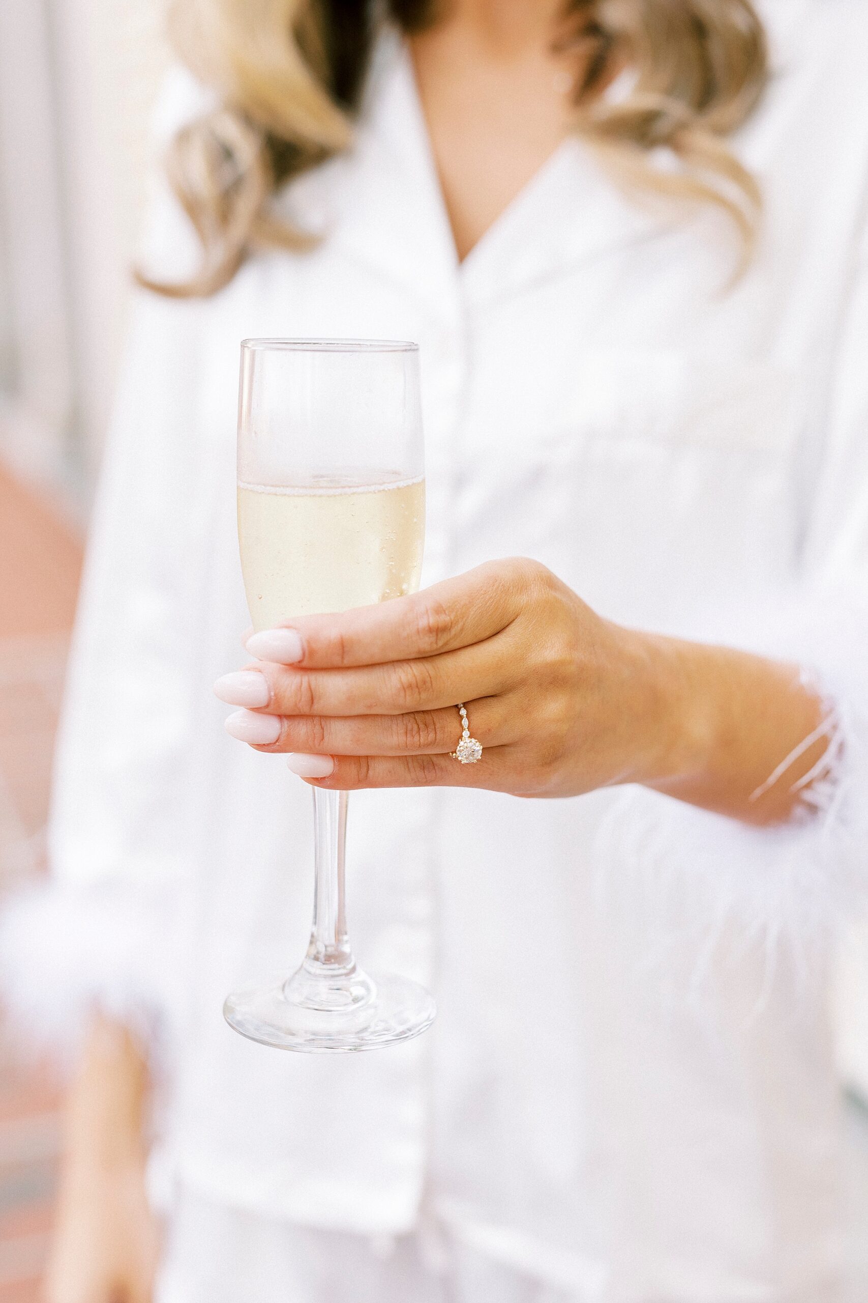 bride holds glass of champagne showing off engagement ring 