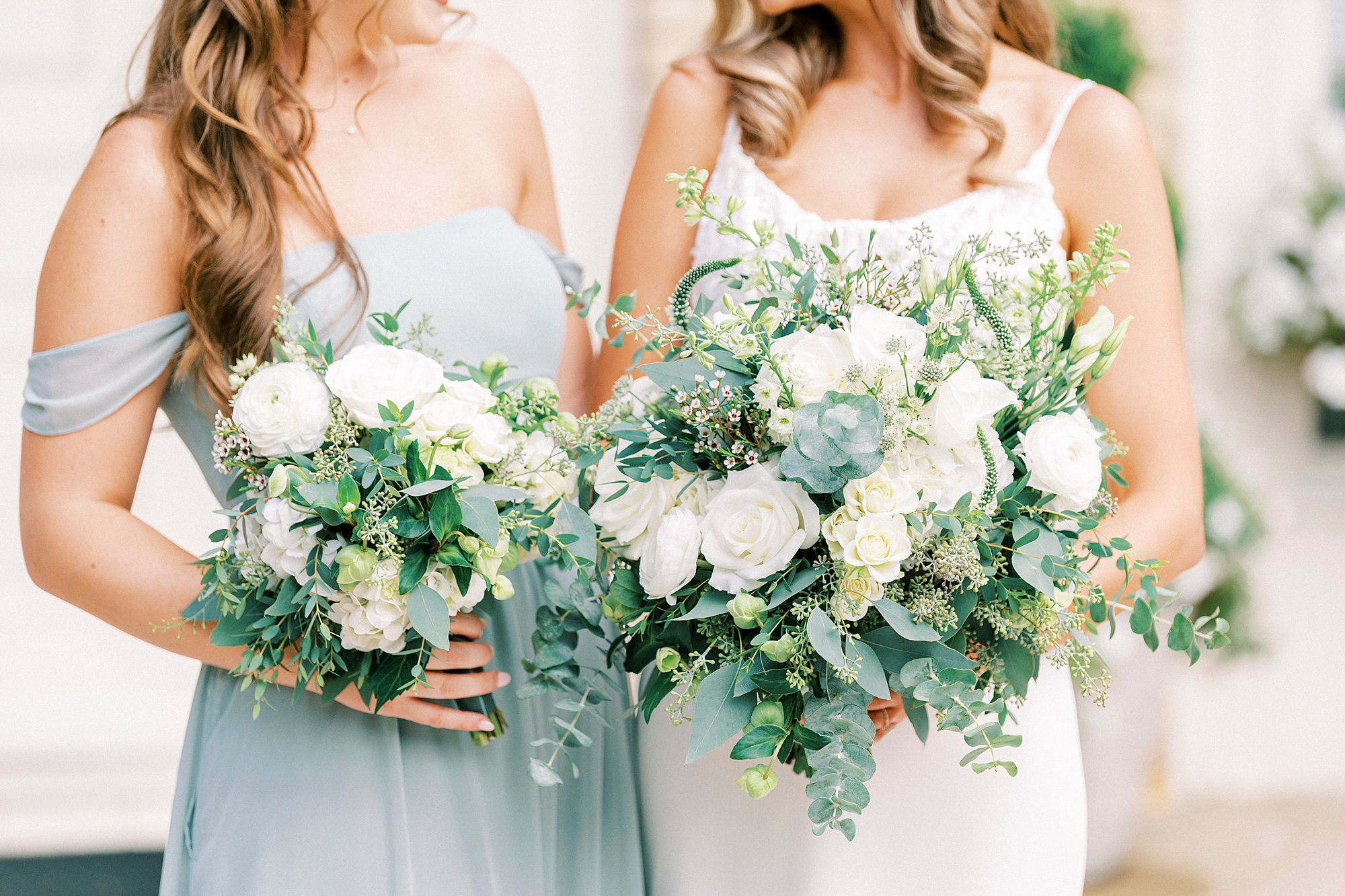 bride poses with bridesmaids with bouquet of ivory flowers 