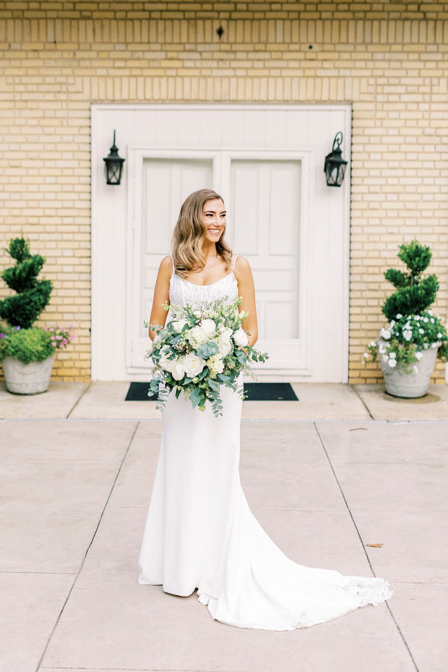 bride holds bouquet of white flowers looking over shoulder in front of white doors at Separk Mansion