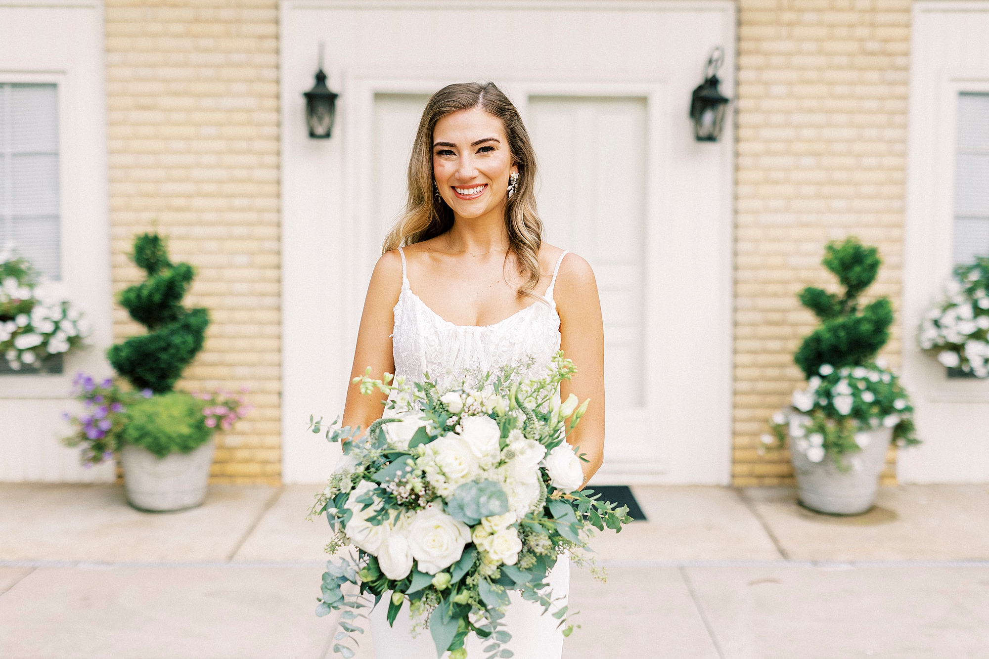 bride holds bouquet of white and green flowers outside Separk Mansion