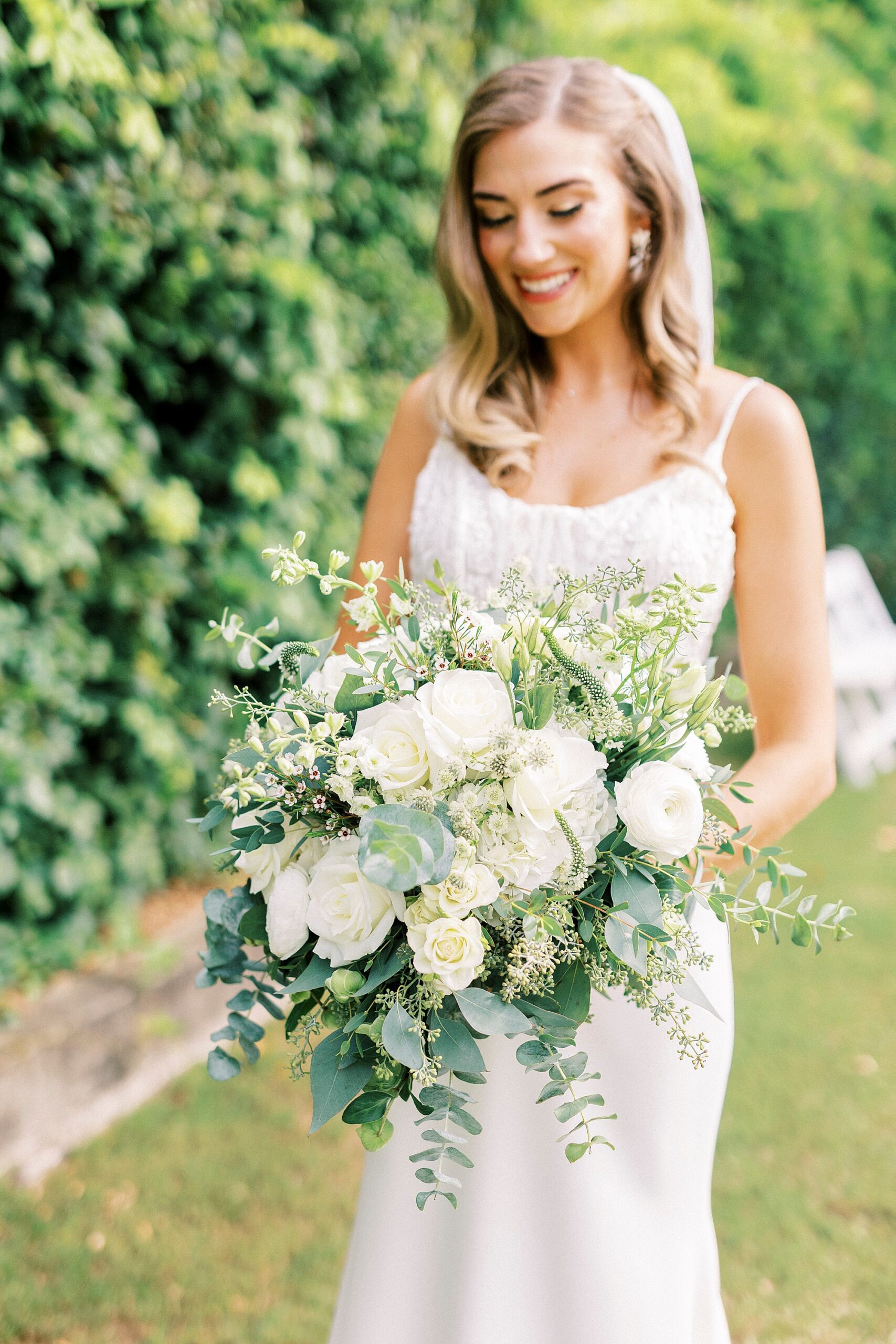 bride holds bouquet of white flowers with greenery and baby's breath 