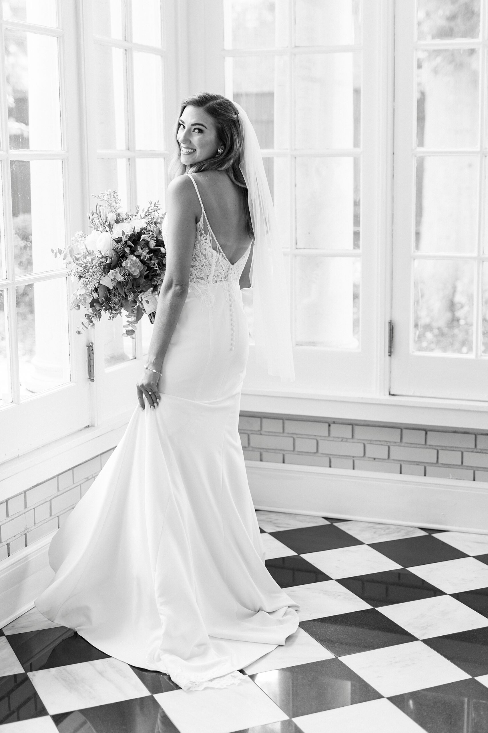 bride holds bouquet and turns in wedding dress on black and white floor of Separk Mansion
