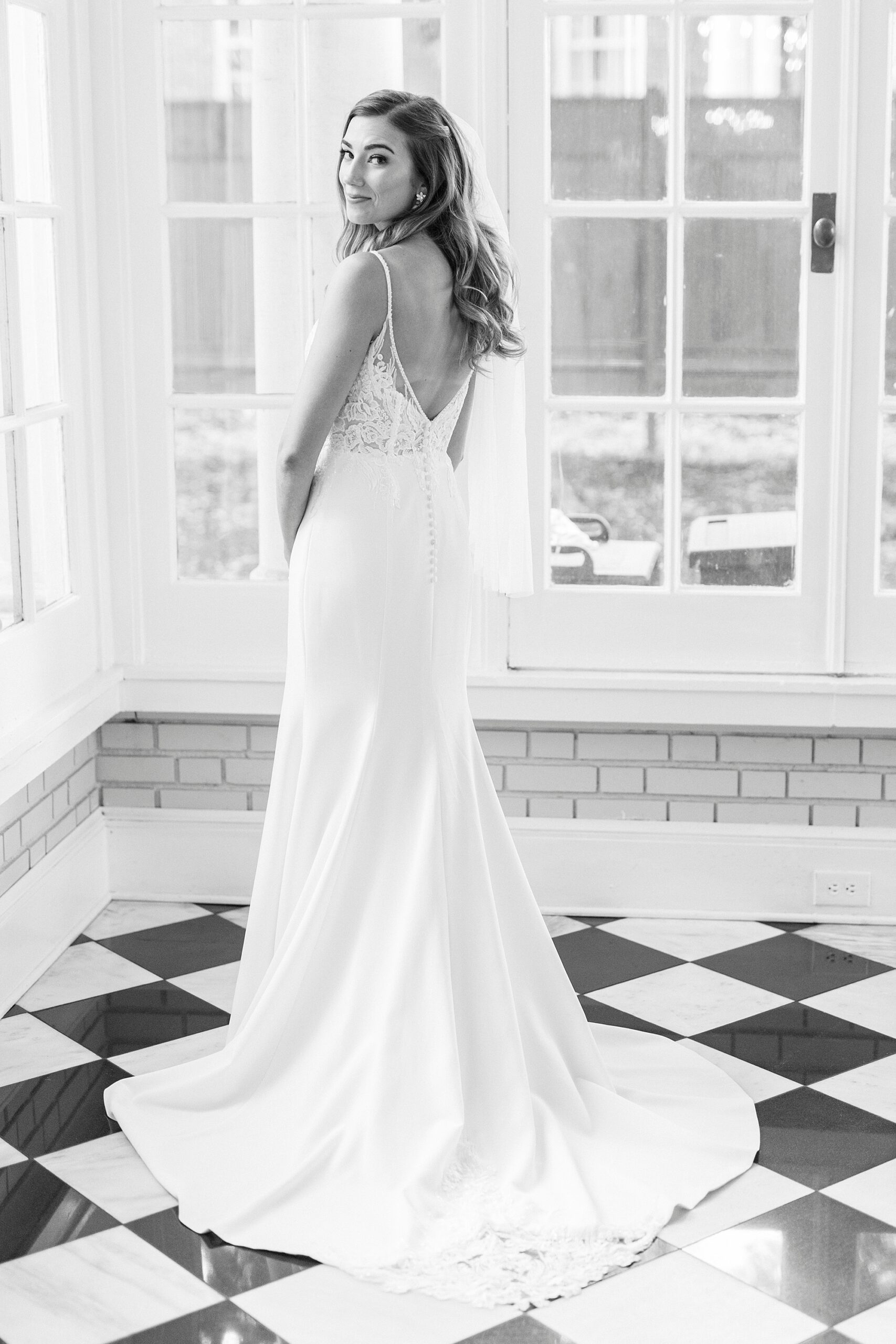 black and white photo of bride showing off back of wedding gown