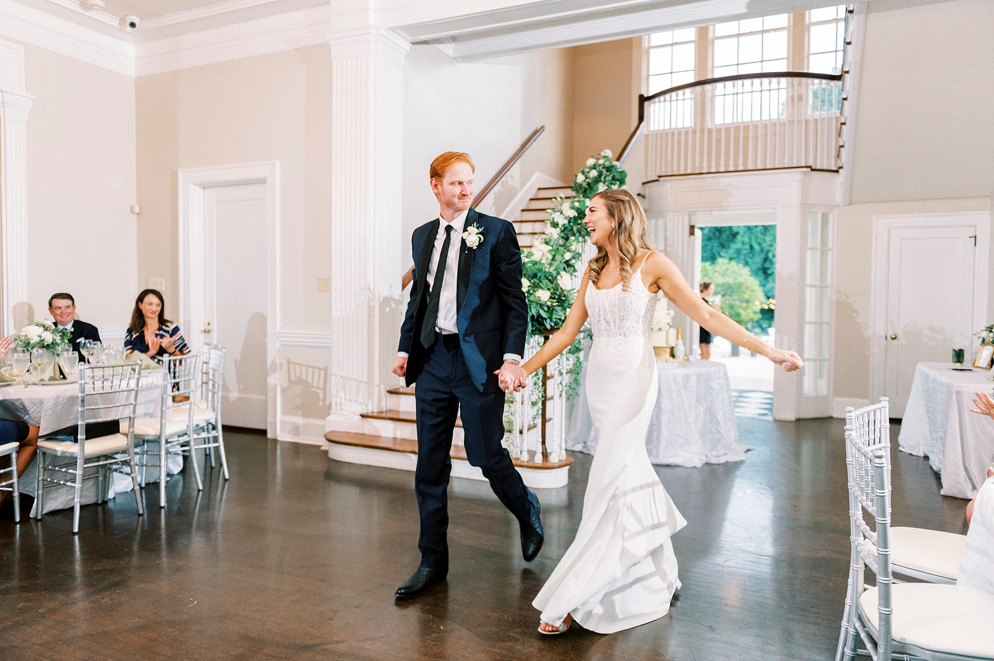 newlyweds hold hands walking through Separk Mansion wedding reception 