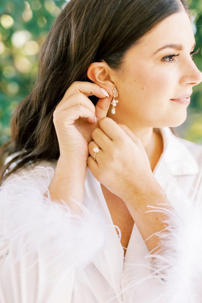 bride adjusts small gold earrings before NC wedding day 