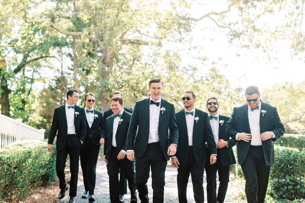 groom walks with groomsmen in black suits in Charlotte NC 
