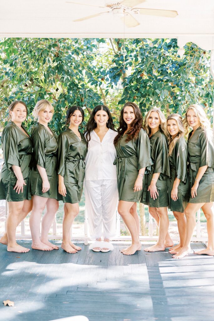 bride poses with bridesmaids in sage green robes at Whitehead Manor