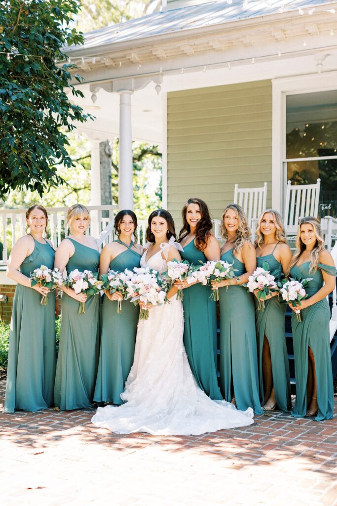 bride poses with bridesmaids in green bridesmaid gowns for fall wedding at Whitehead Manor