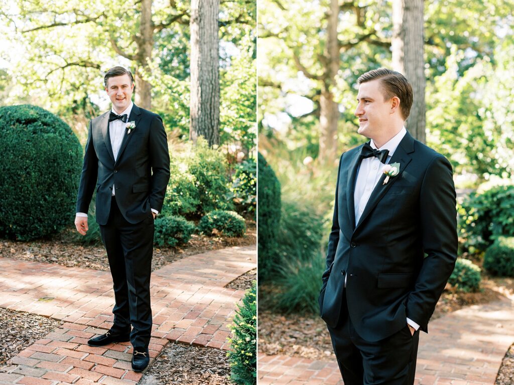 groom stands with hands in pockets of black suit 