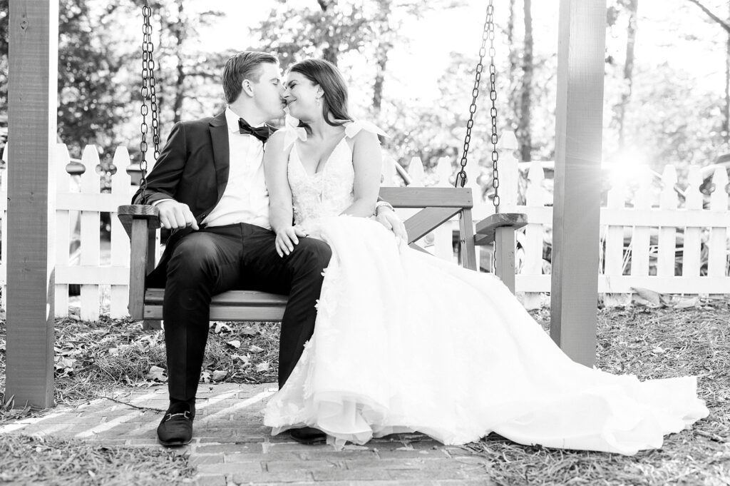 black and white portrait of bride and groom sitting on wooden bench at Whitehead Manor