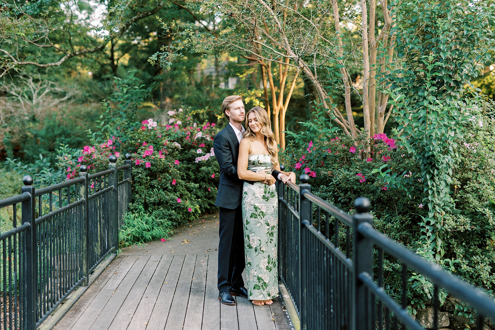engaged couple hugs on bridge in Glencairn Garden during engagement portraits 